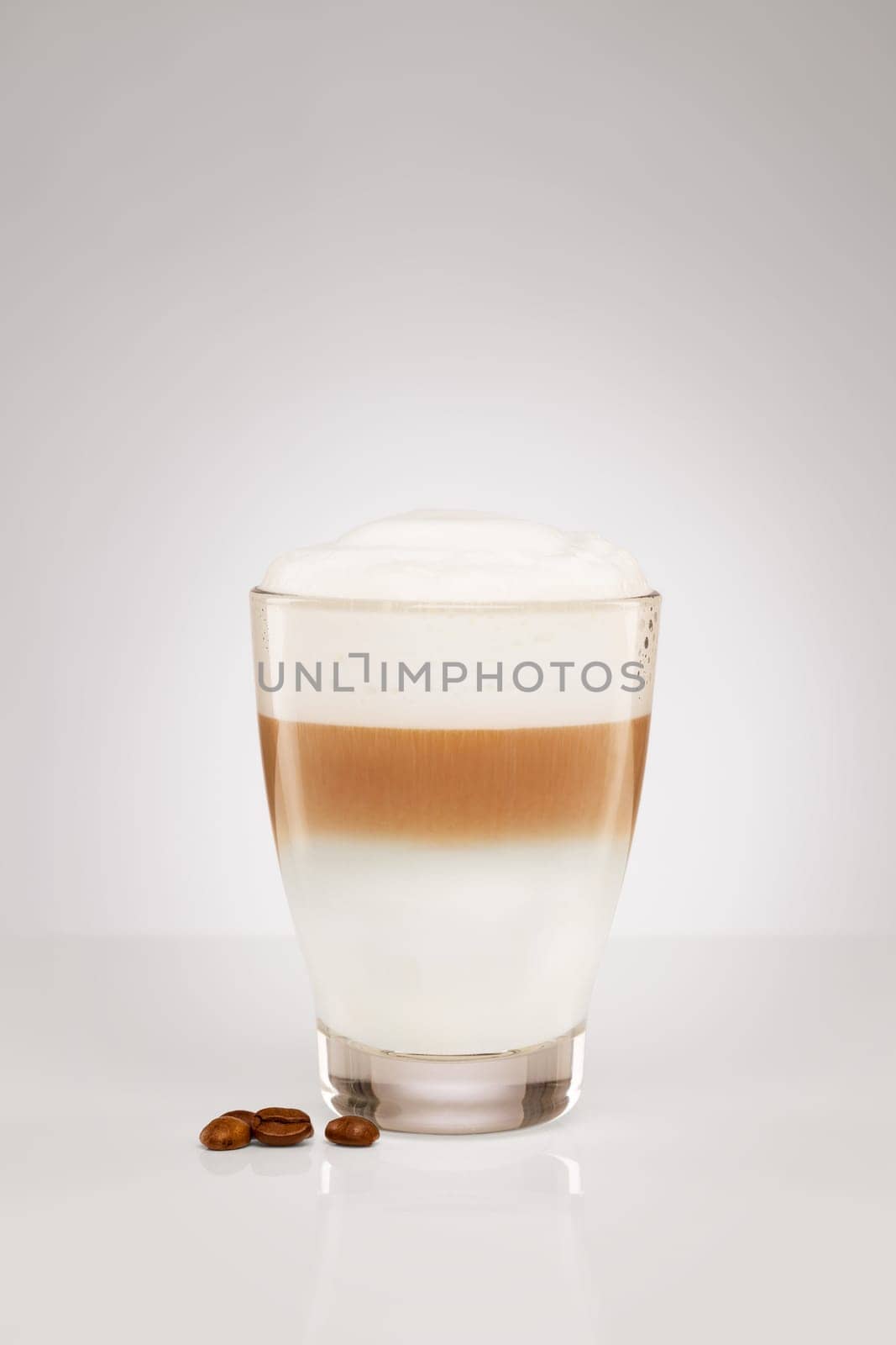 Small latte macchiato with coffee beans on grey background