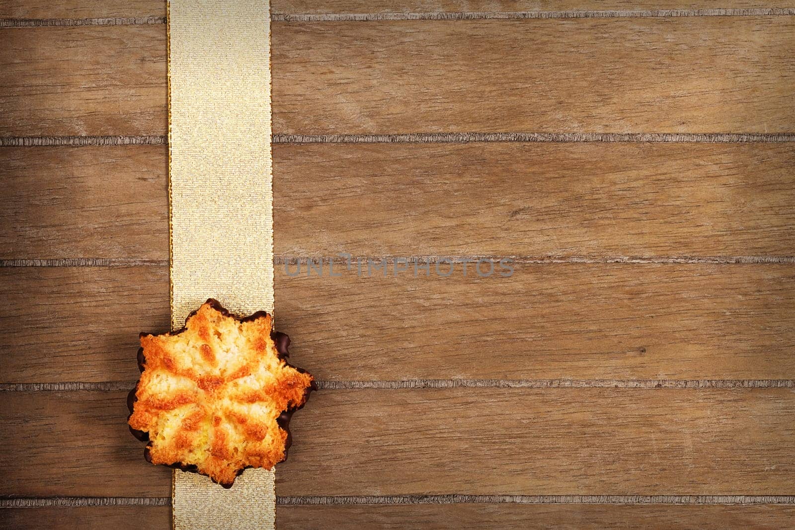Coconut Christmas cookies on golden ribbon on wooden background