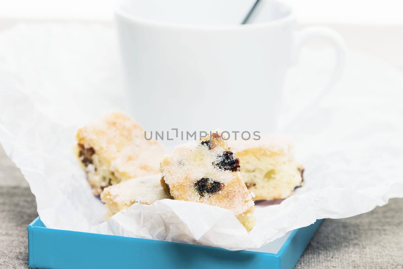 Small pieces of Christmas stollen on baking paper in front of a white cup