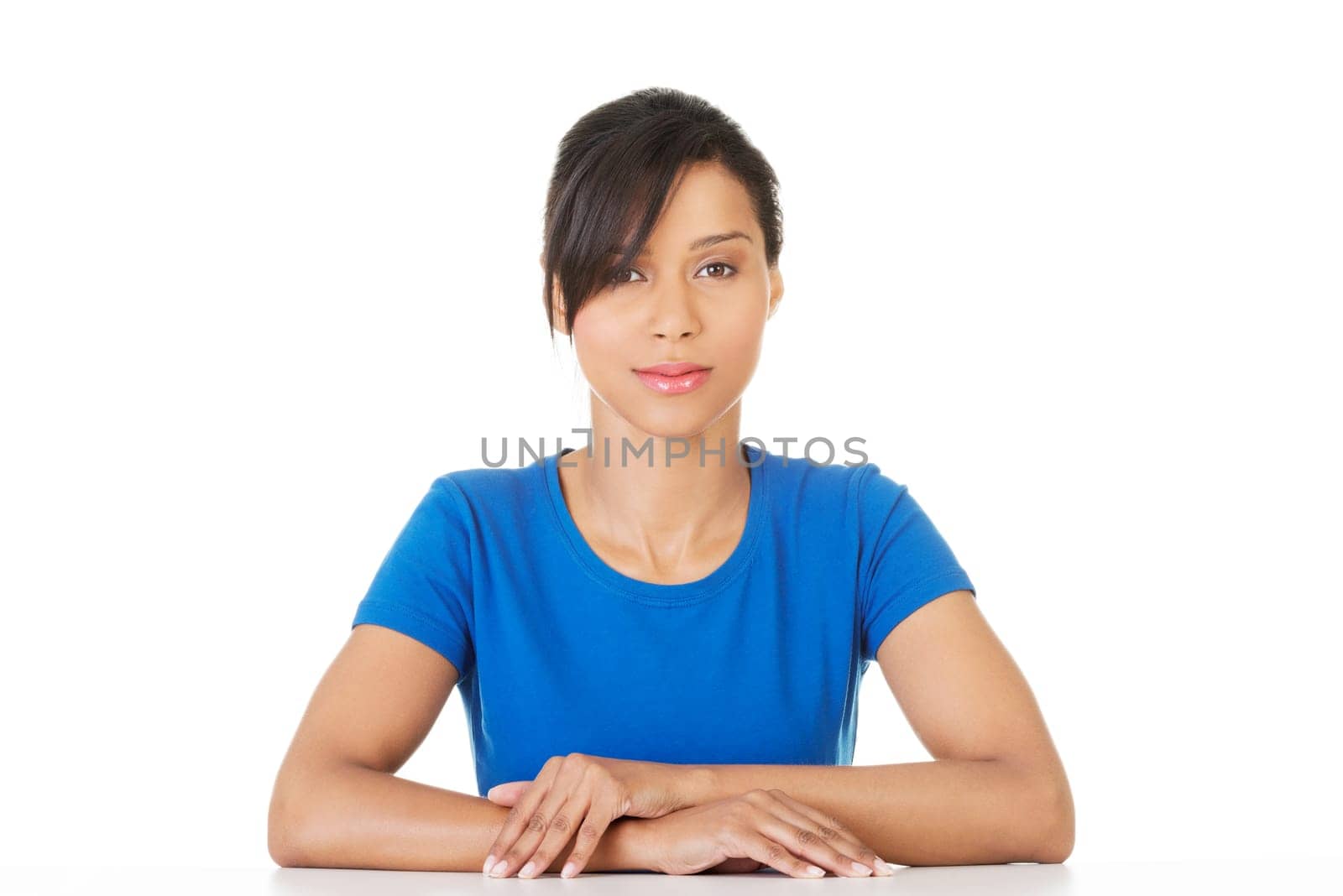 Pretty, happy, young woman in casual clothes sitting at the desk, isolated on white