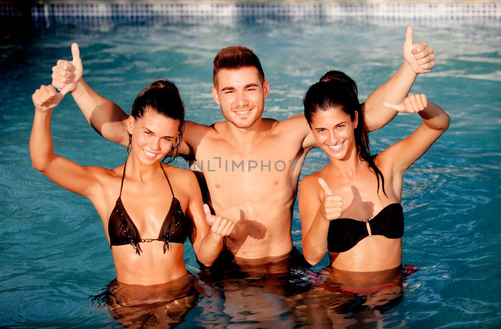 Three happy friends in the pool with a blue water of background saying Ok