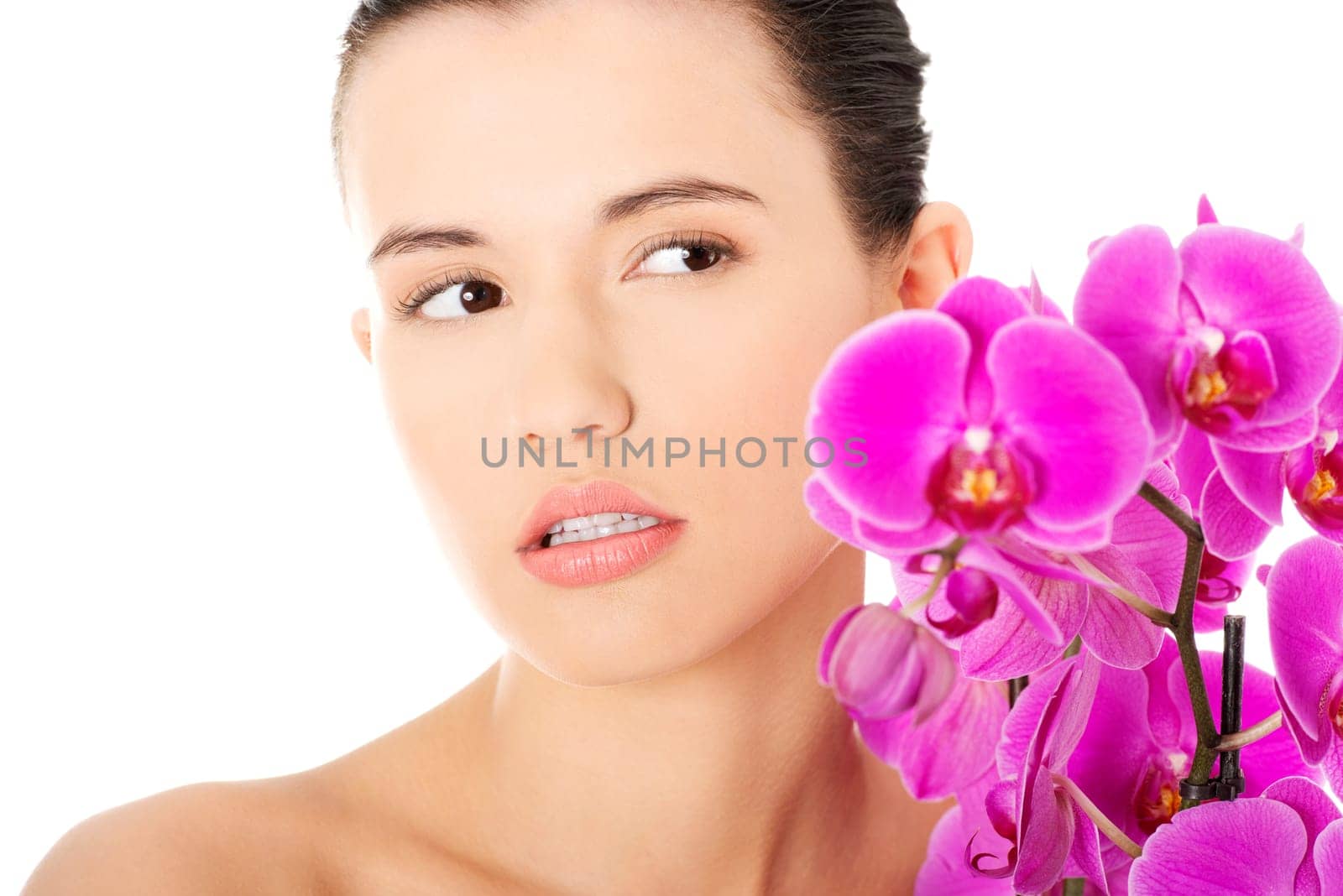 Portrait of beautiful young woman with health skin and with orchid flower. Spa concept.