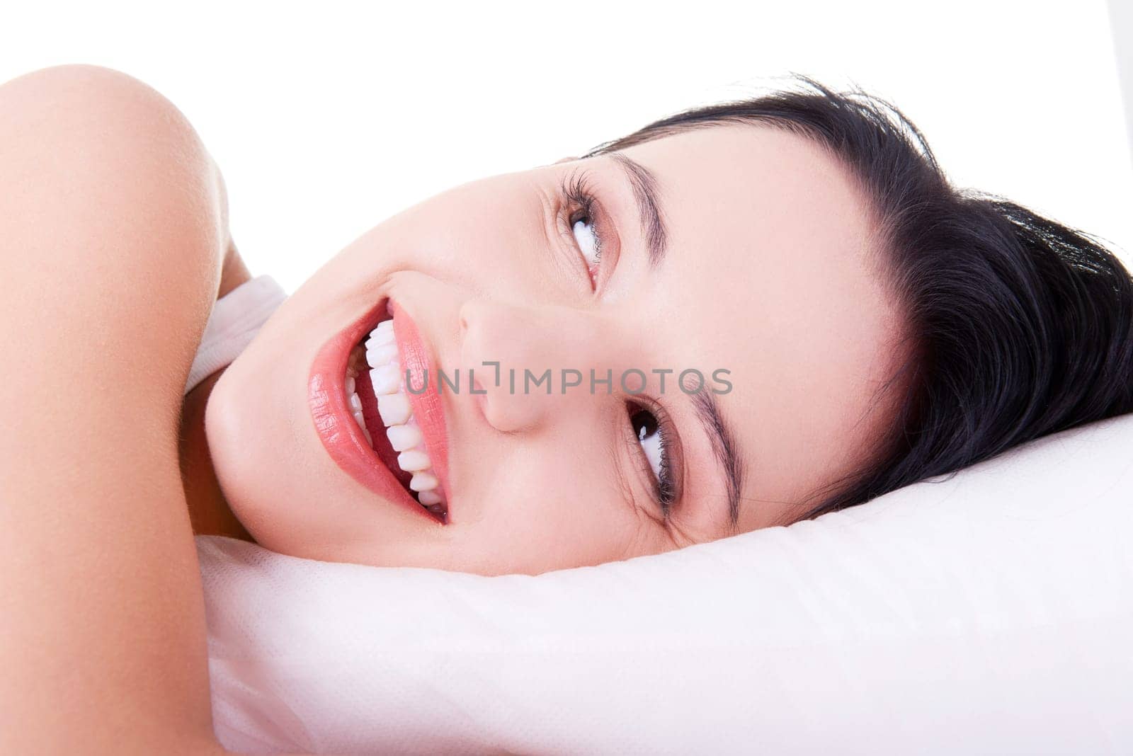 Happy sensual young woman lying in bed and smiling to camera