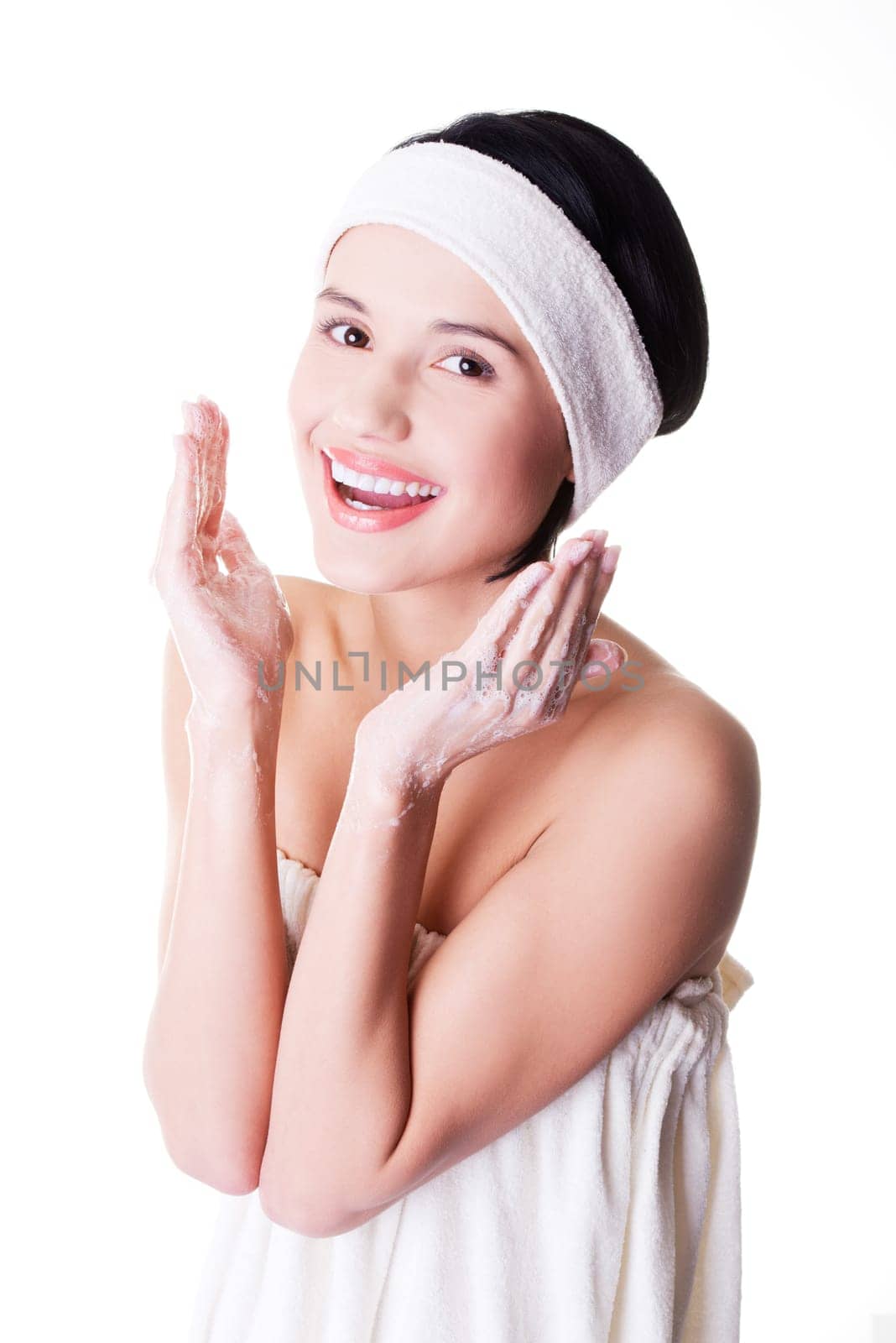 Beautiful happy woman is cleaning her face