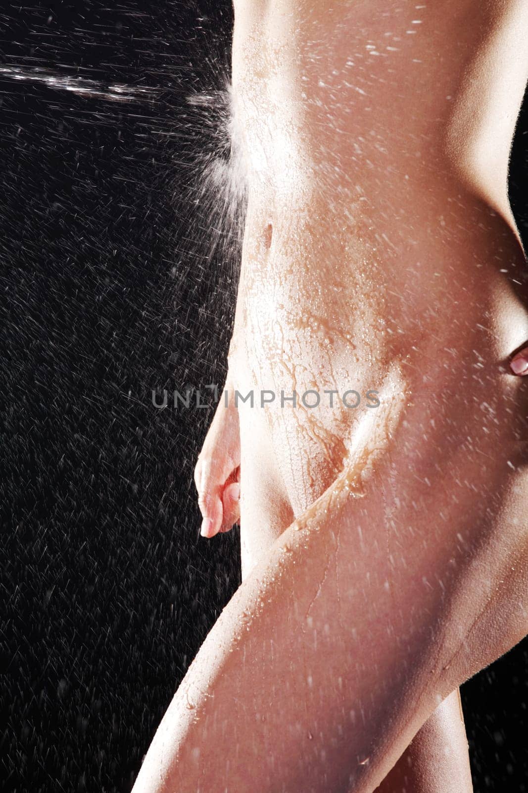 Water splashing on fit nude female body over black