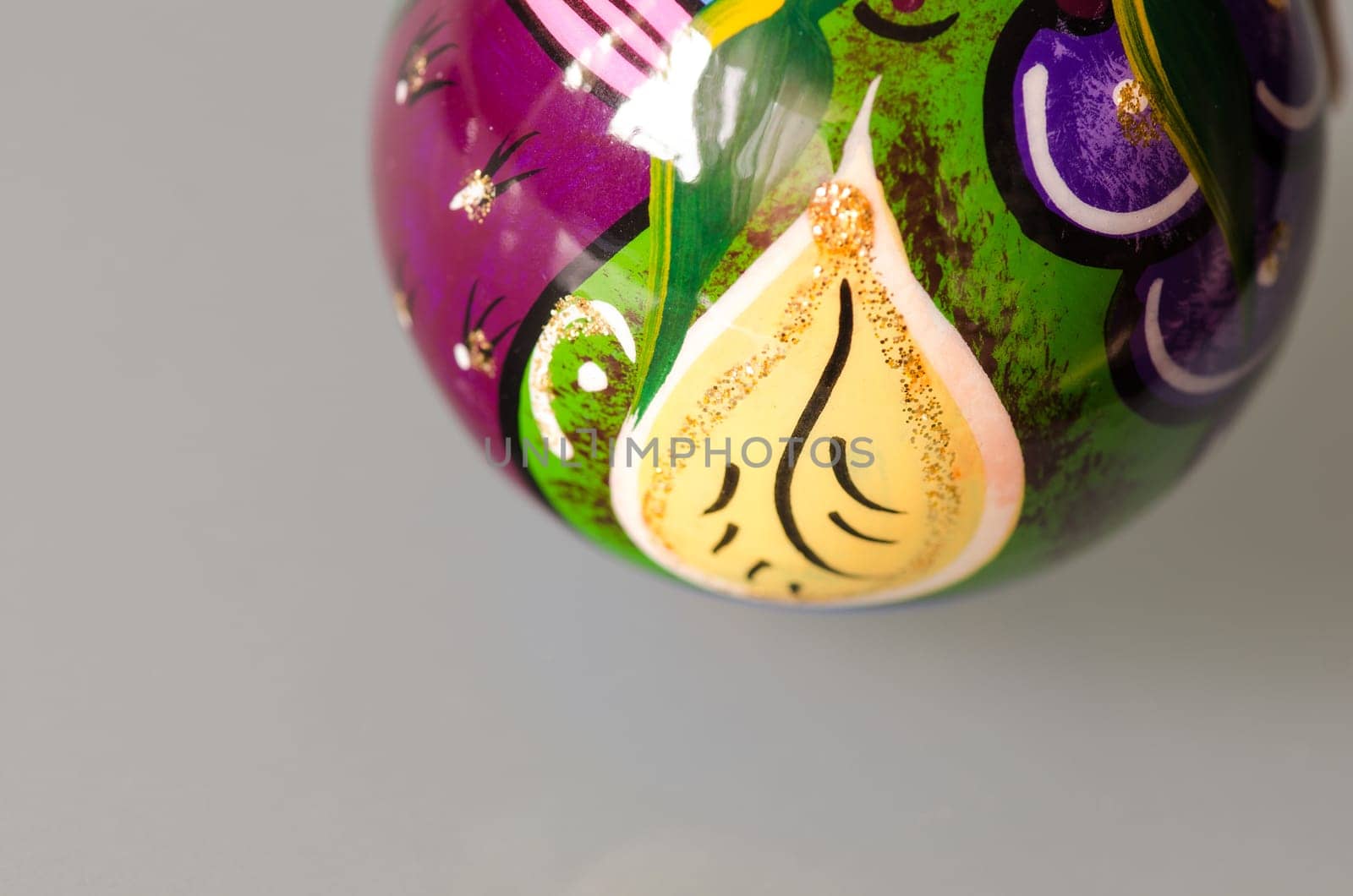 Classic Christmas ball green blue yellow and glossy isolated on grey.