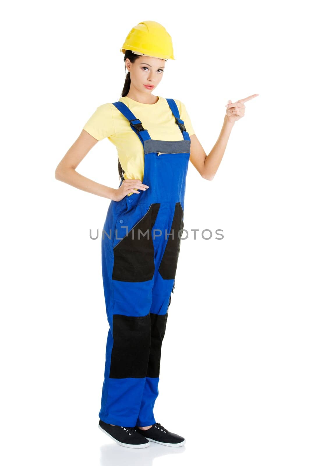 Female construction worker pointing on copy space, isolated on white