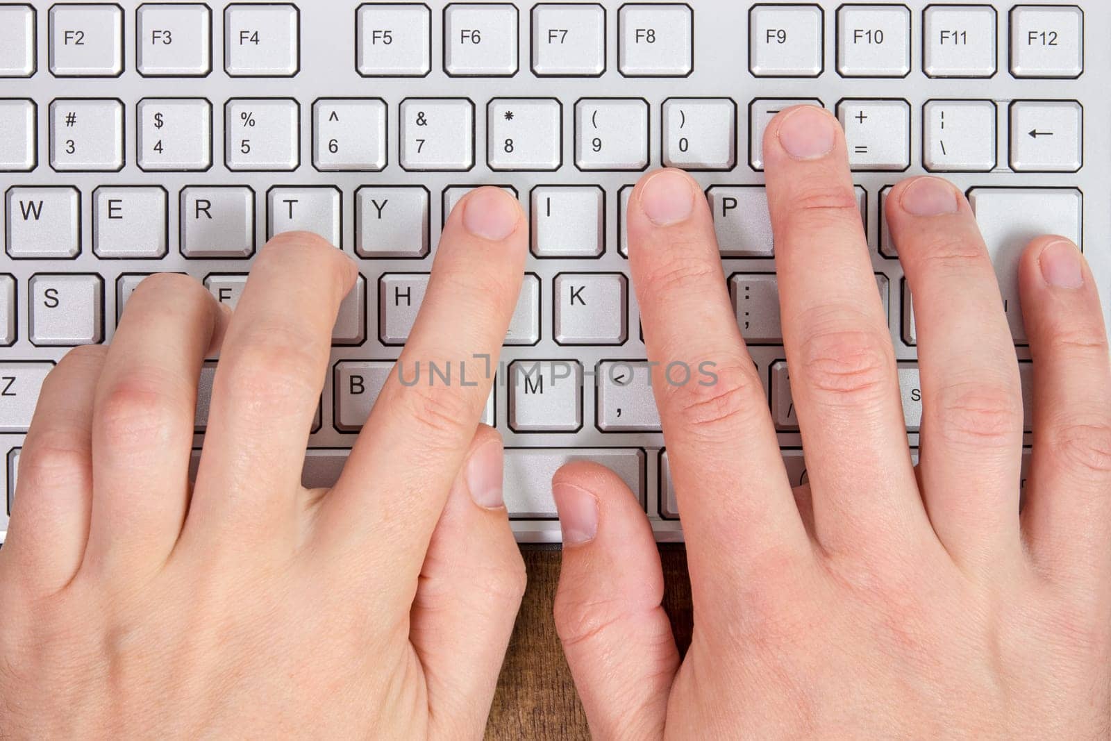 Hands typing on a computer keyboard. View from above.