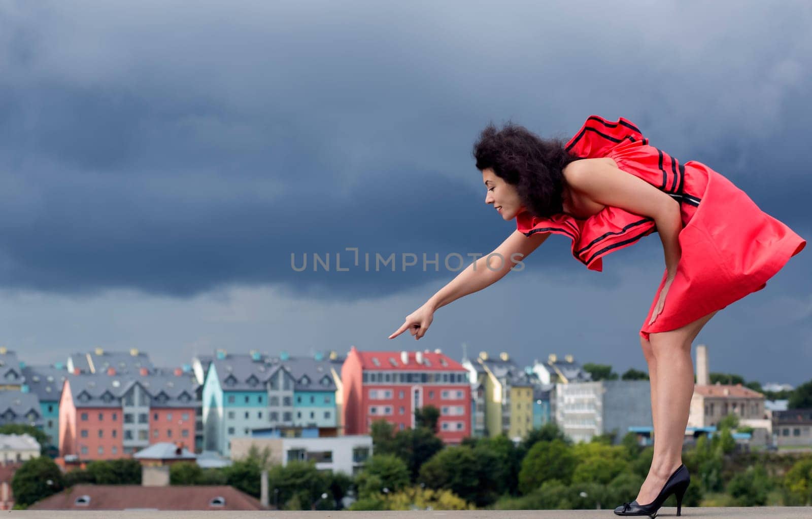 Woman in nice dress pointing on background house