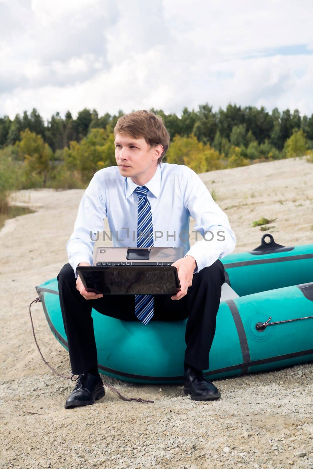Dressed man sit on boat edge with laptop
