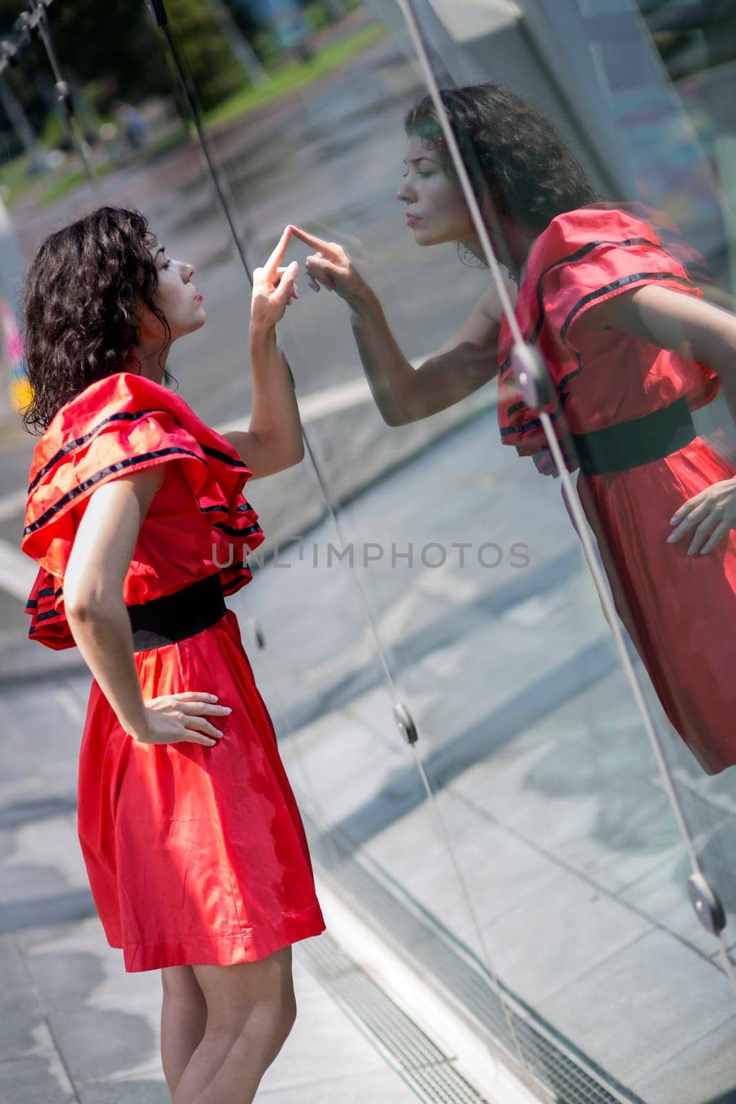 Woman in red dress scratching smooth glass surface