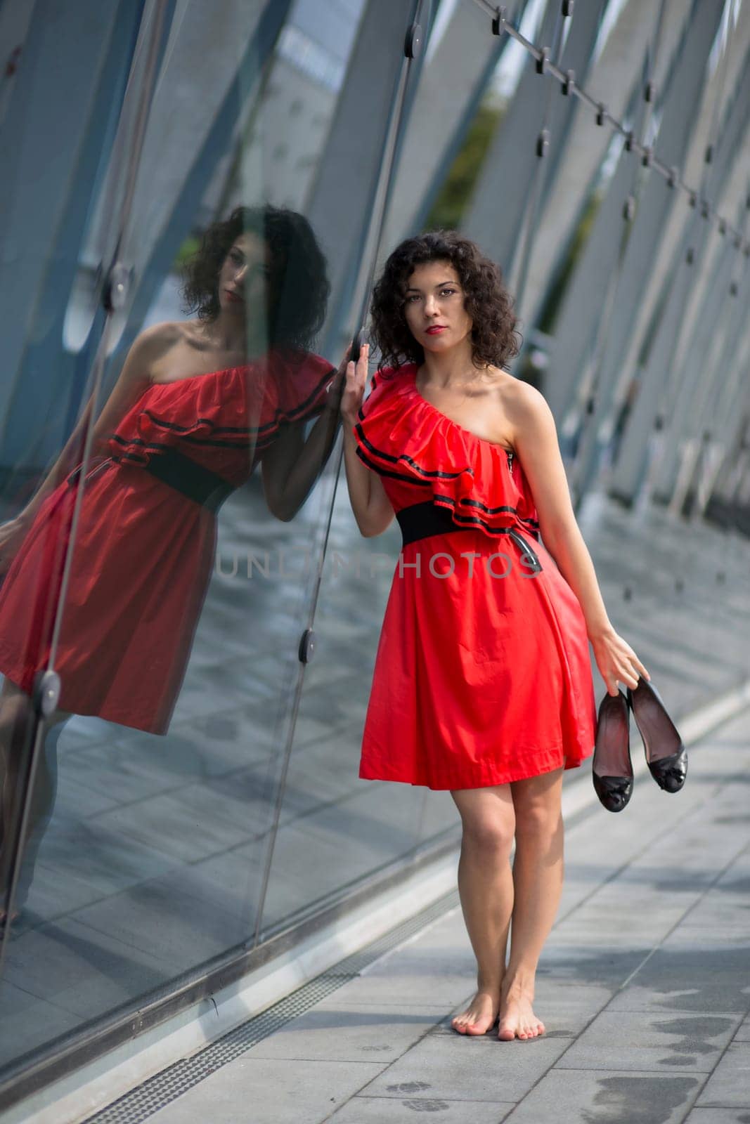 Woman in red dress touch angle glass wall