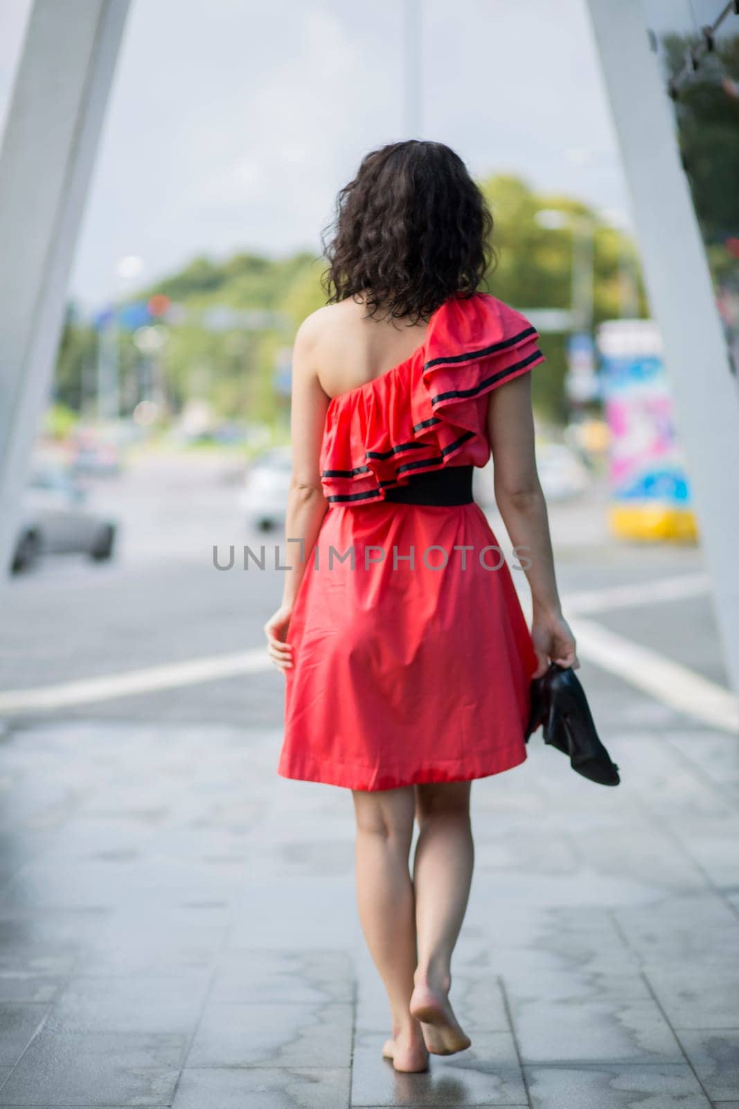 Woman in red dress walking barefoot on square