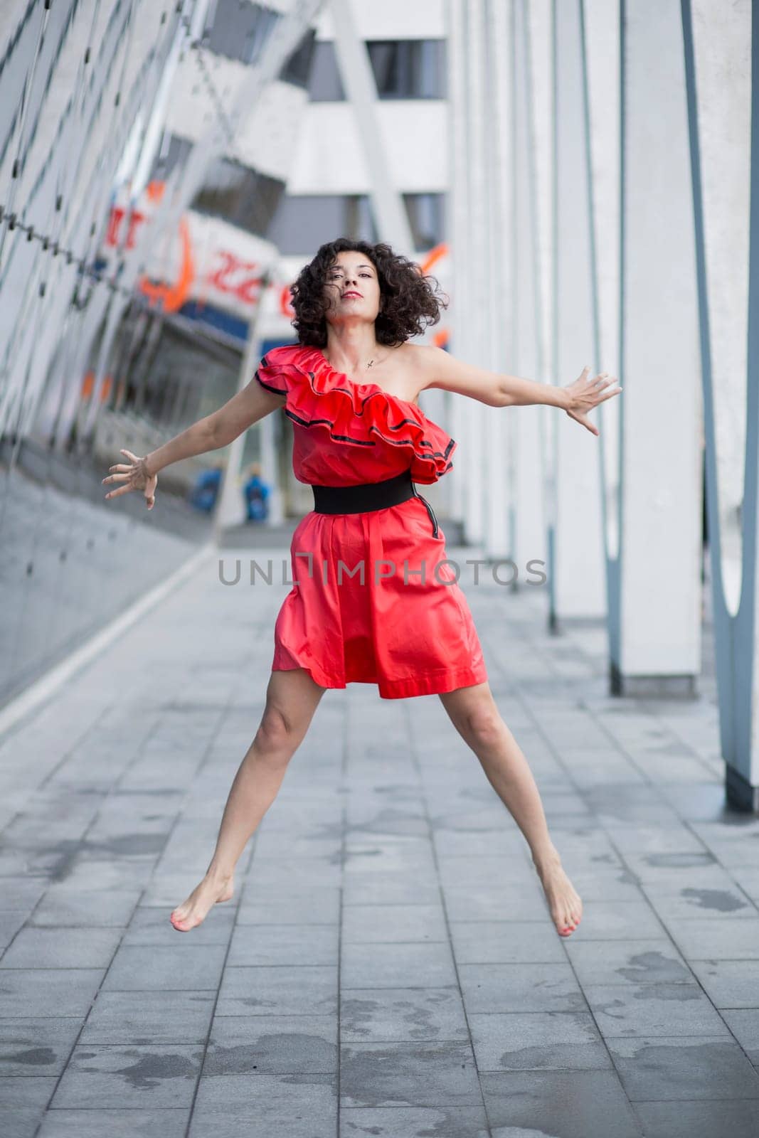Woman in red dress jump both hands behind