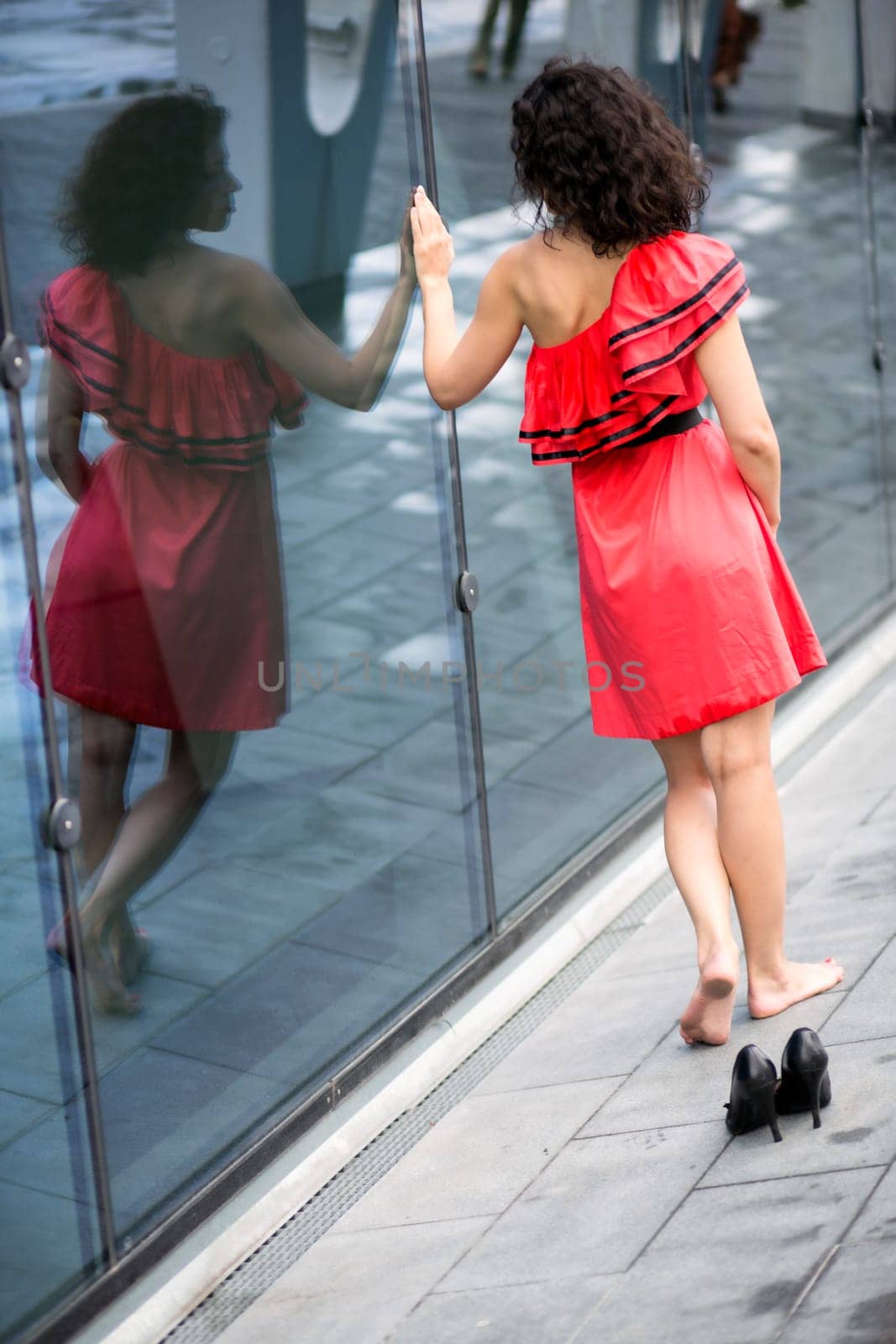 Woman in red dress walk along glass wall