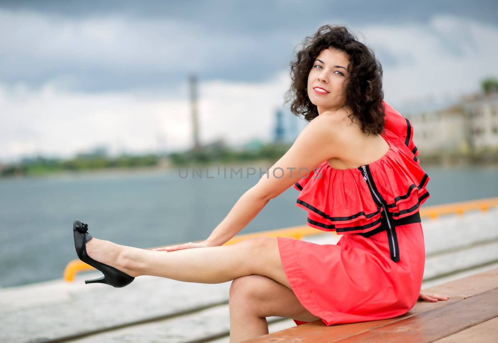Woman in dress stroking leg at city background