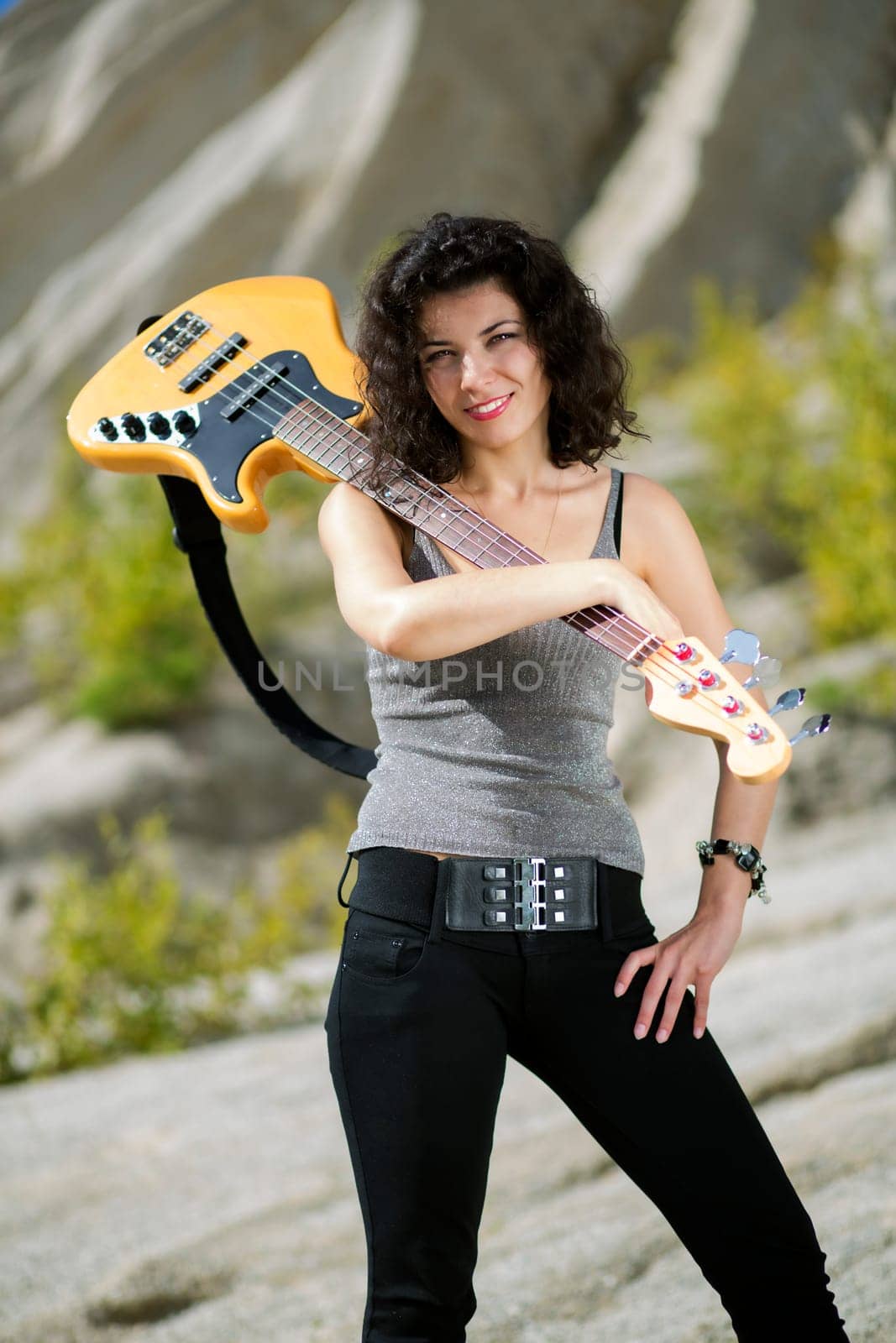 Woman posing with yellow bass guitar over shoulder