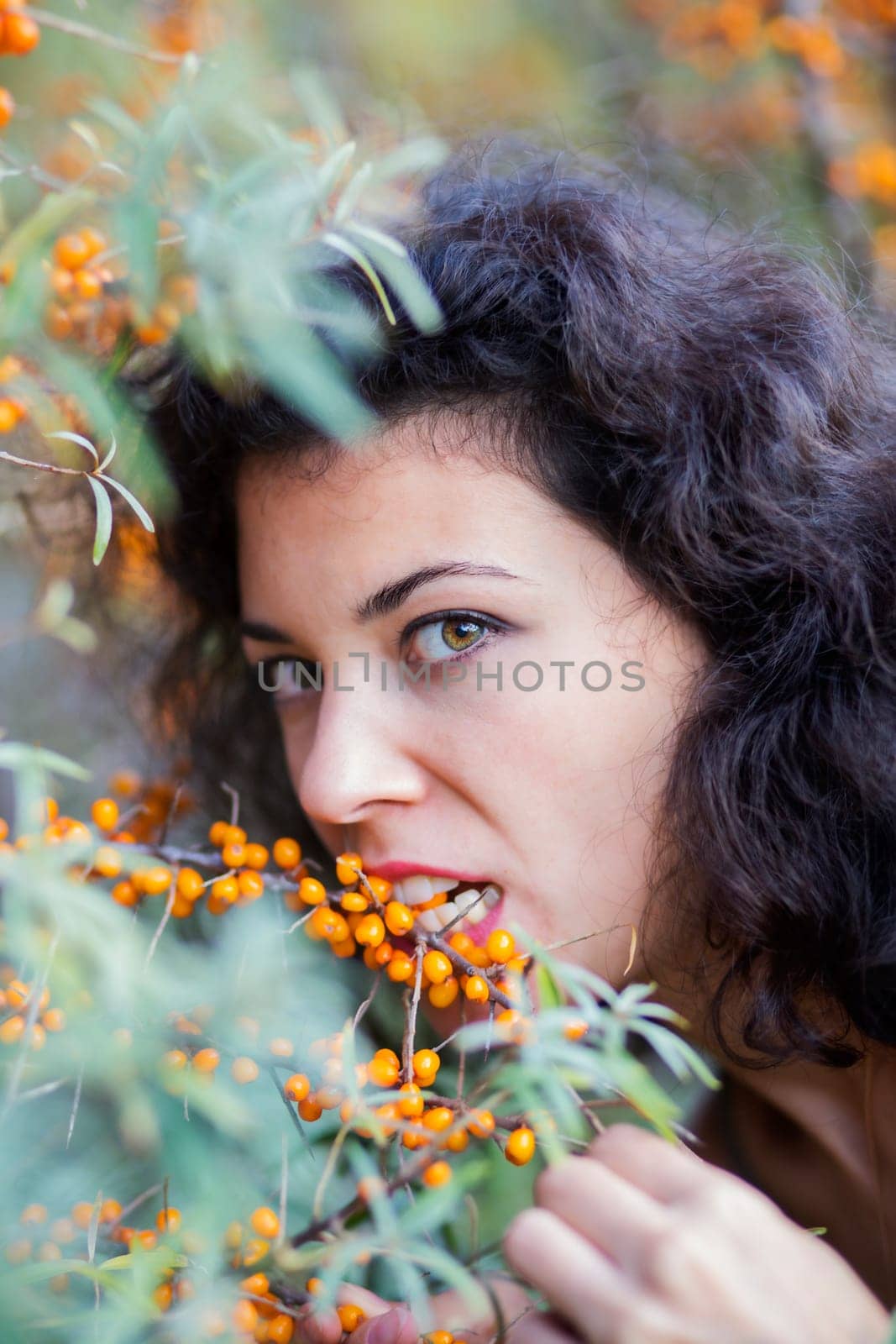Zoomed view of woman bite gooseberries from branch