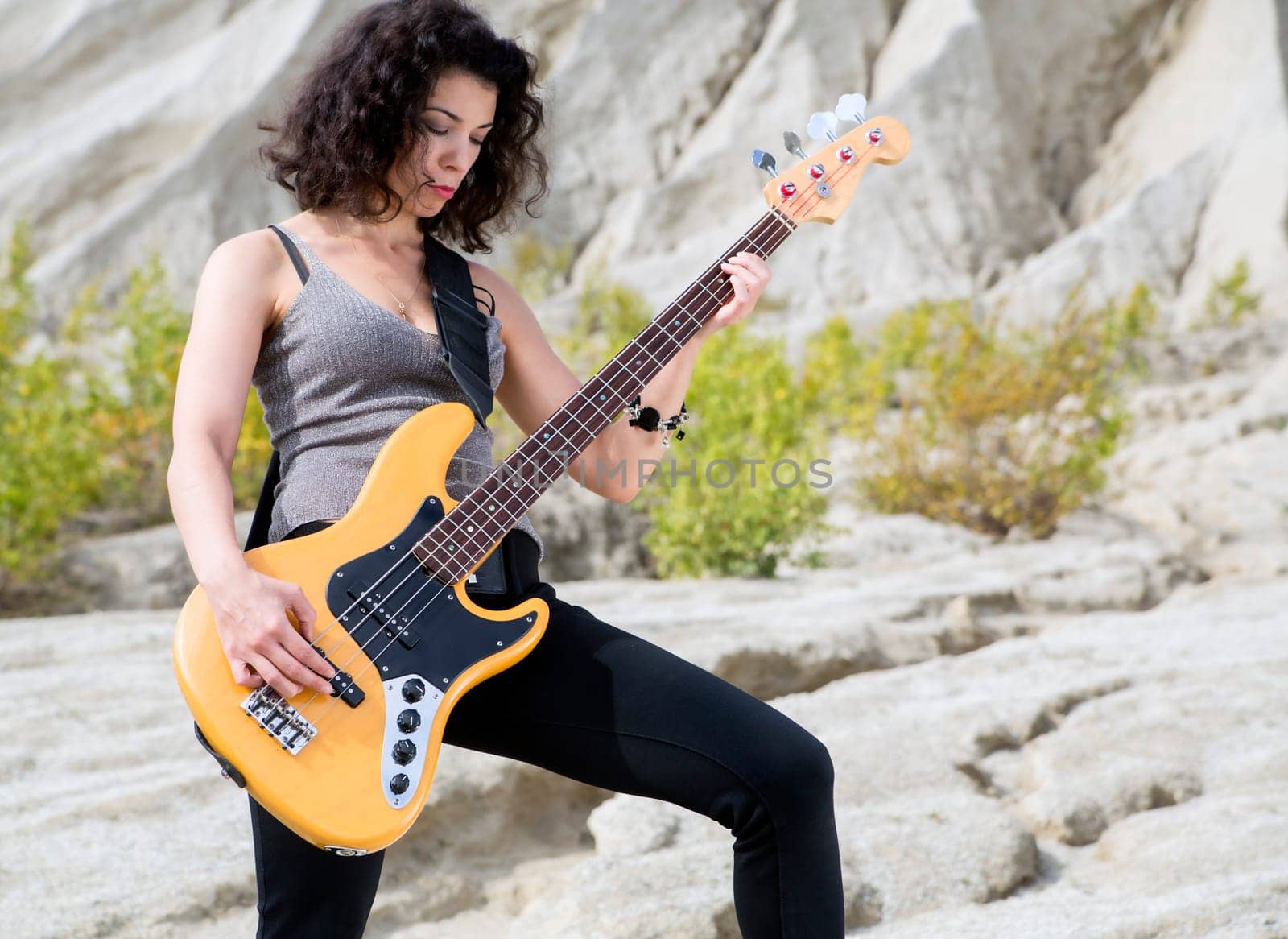 Woman on sandy background posing with yellow guitar