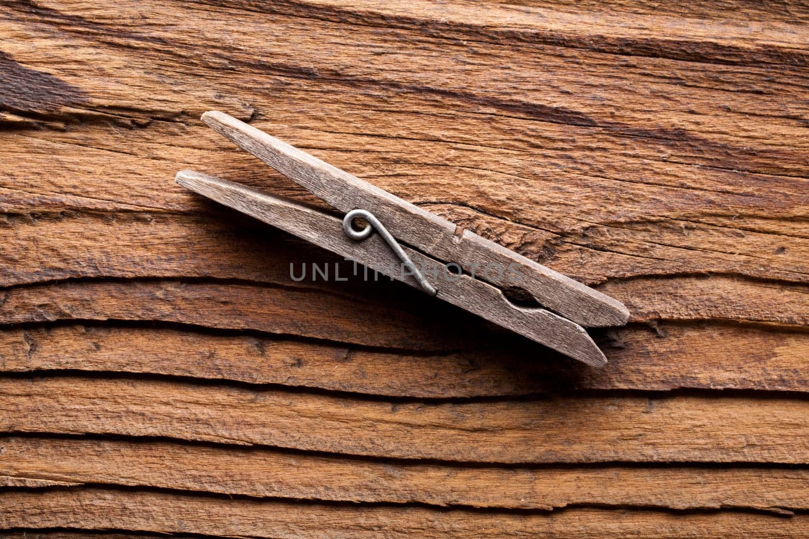 A clothes peg on a dark coarse-grained wooden background