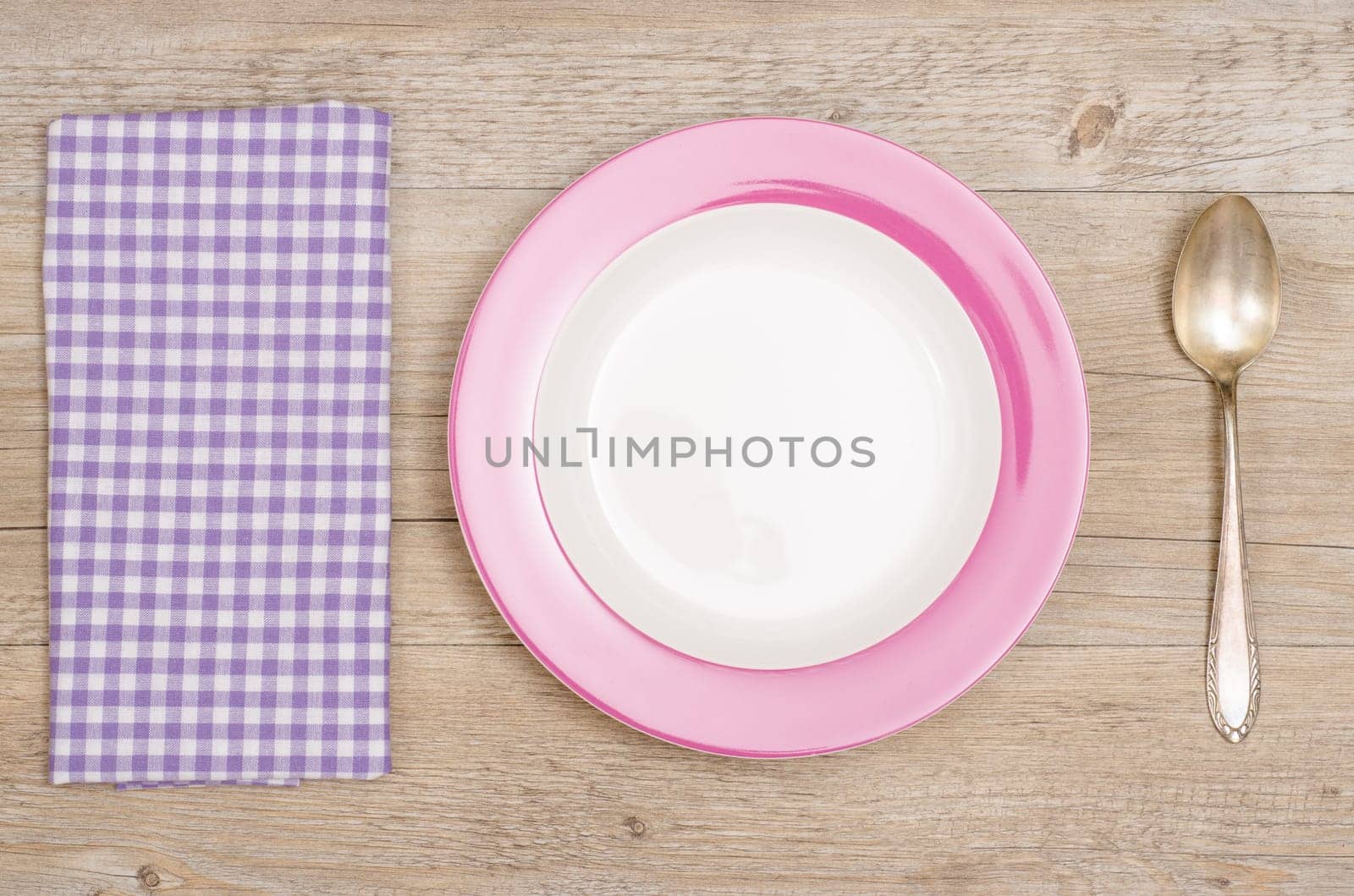Plates,spoons and purple checkered napkin on wood