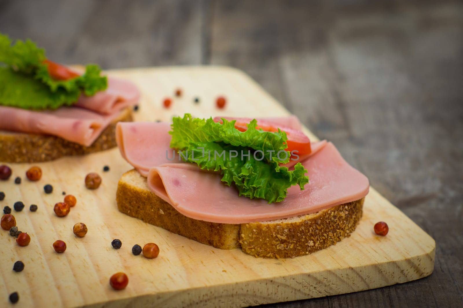Delicious ham sandwiches on wooden textured background.