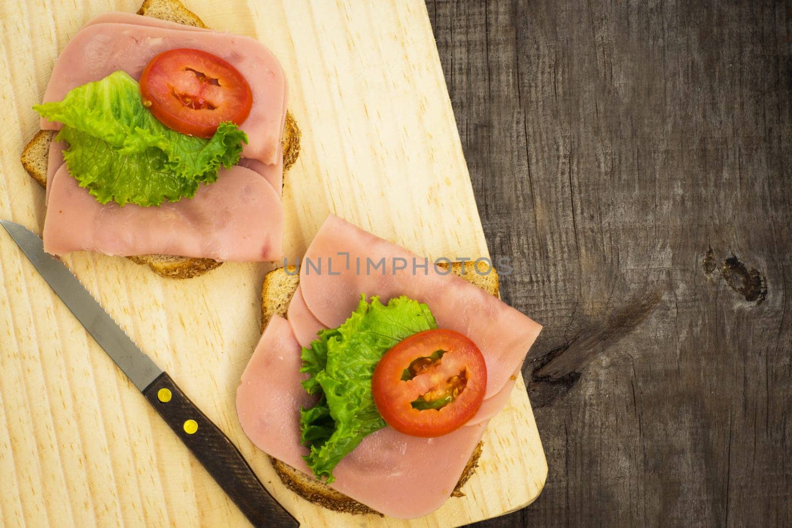Delicious ham sandwiches on wooden textured background.