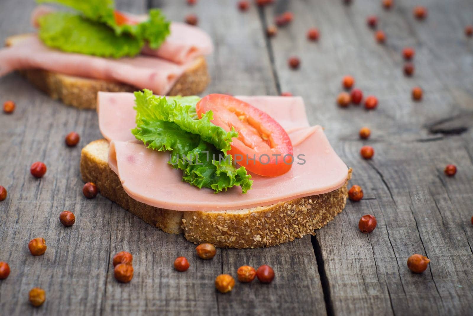 Delicious ham sandwiches on wooden textured background.