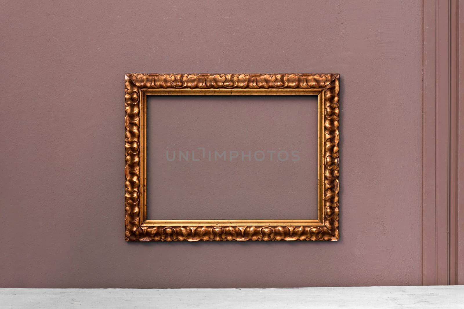 Ornate gold wooden vintage picture frame hanging on an interior wall ready for your artwork or painting in an interior decor concept