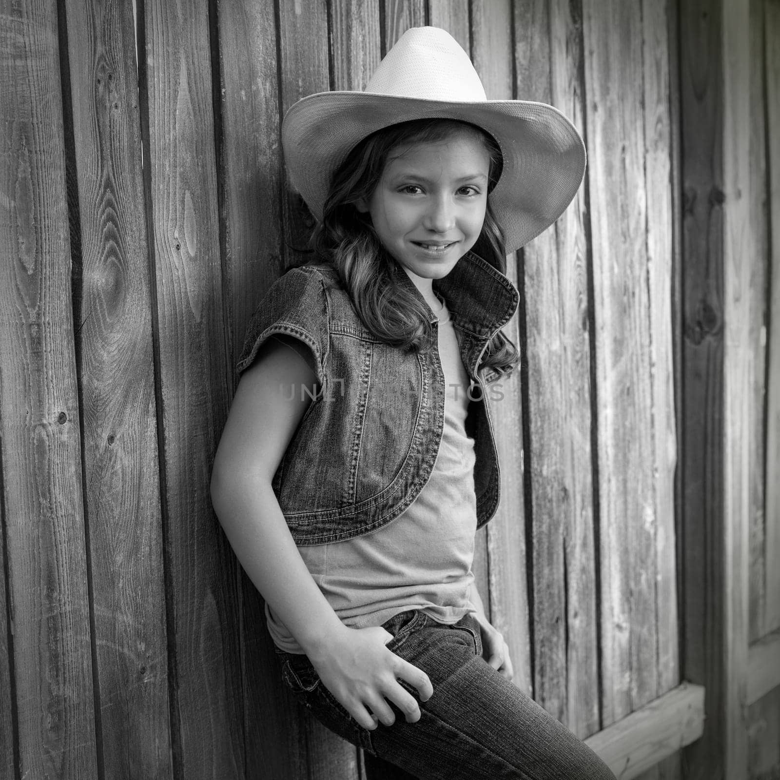 Children girl as kid cowboy girl cowgirl posing on wooden fence far west style