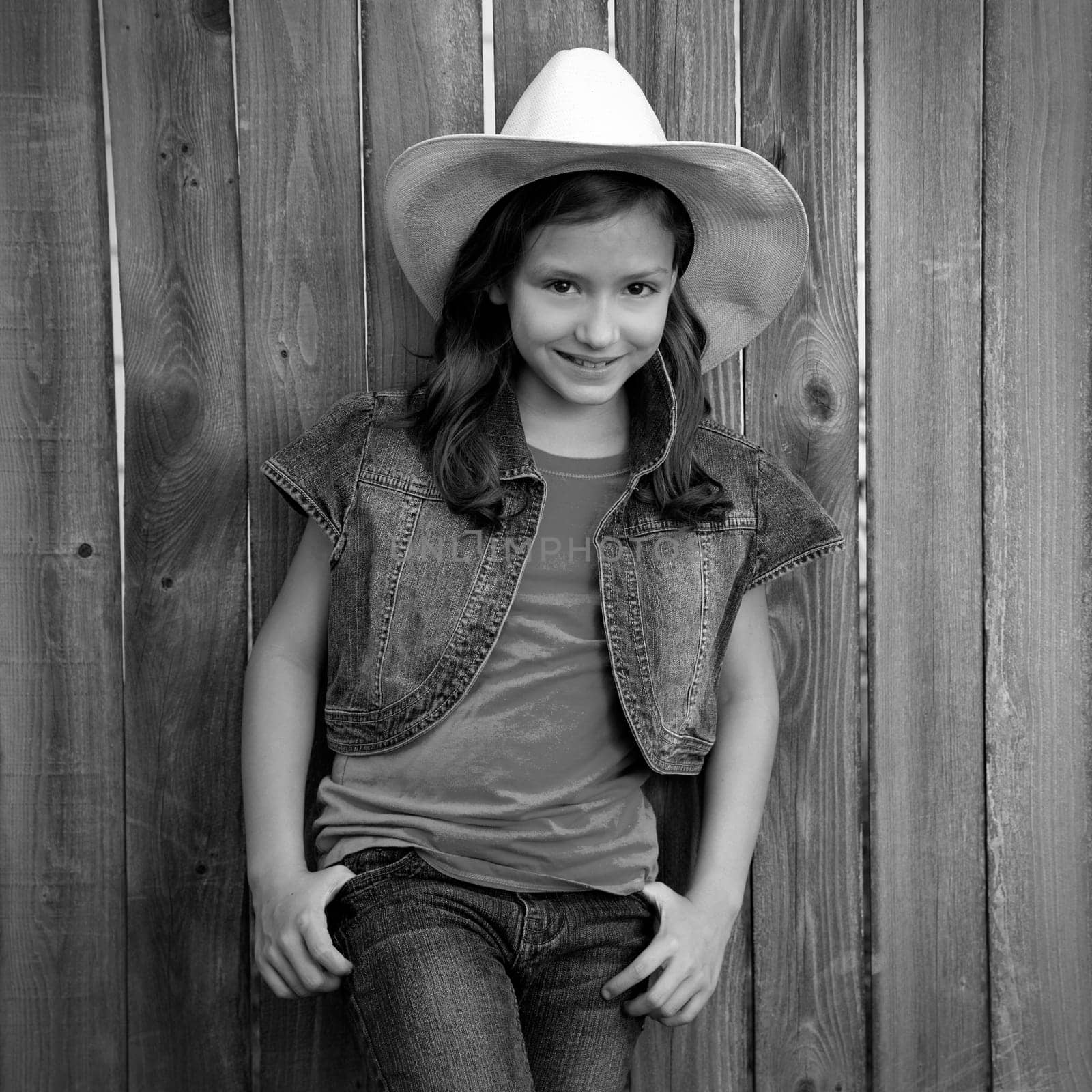 Children girl as kid cowboy girl cowgirl posing on wooden fence far west style