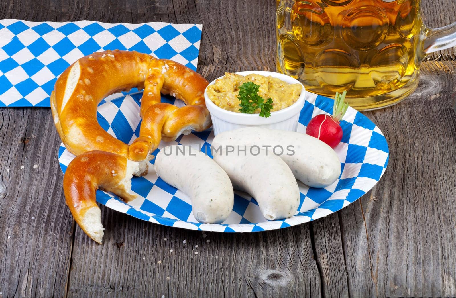 Typical Bavarian Oktoberfest meal with veal sausage,mustard,pretzels and a cool beer on a blue and white paper plate