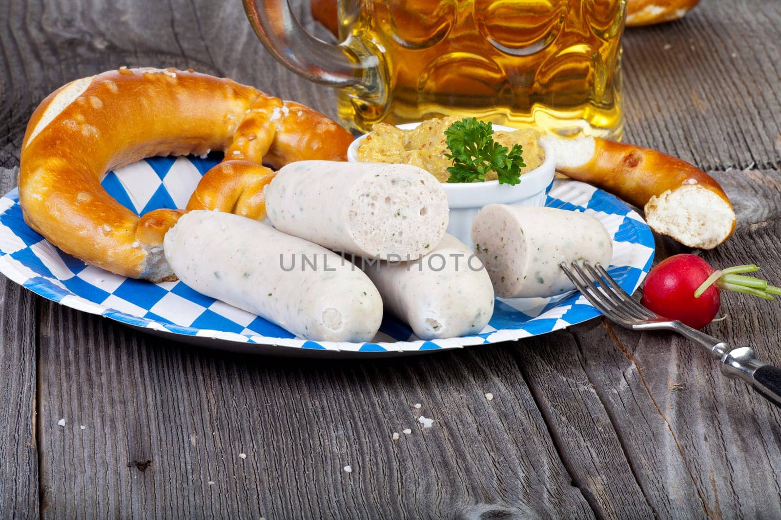 White sausage with mustard,pretzel and a beer on a rustic wooden table