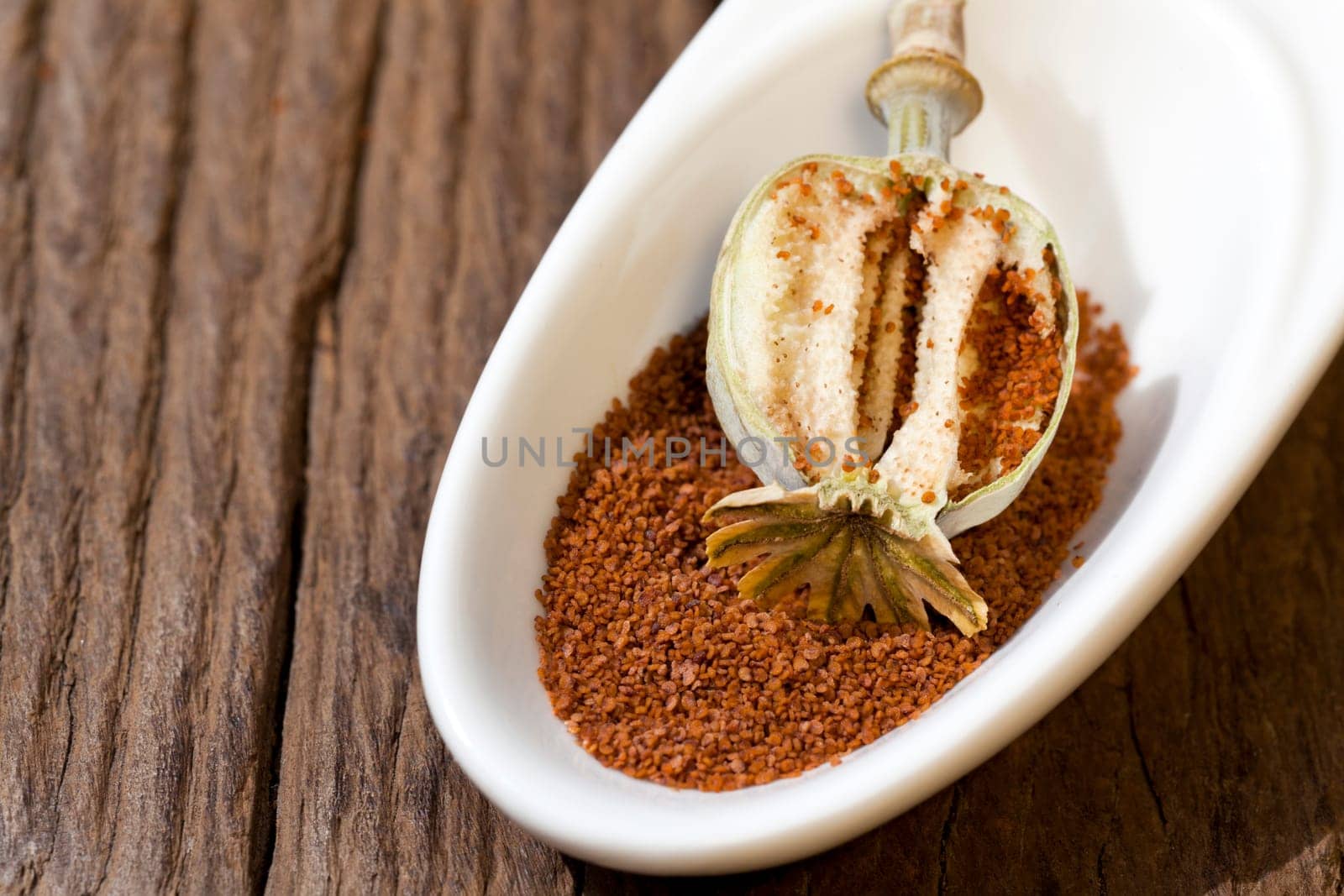 Sliced poppy capsule lies in a bowl of poppy seeds