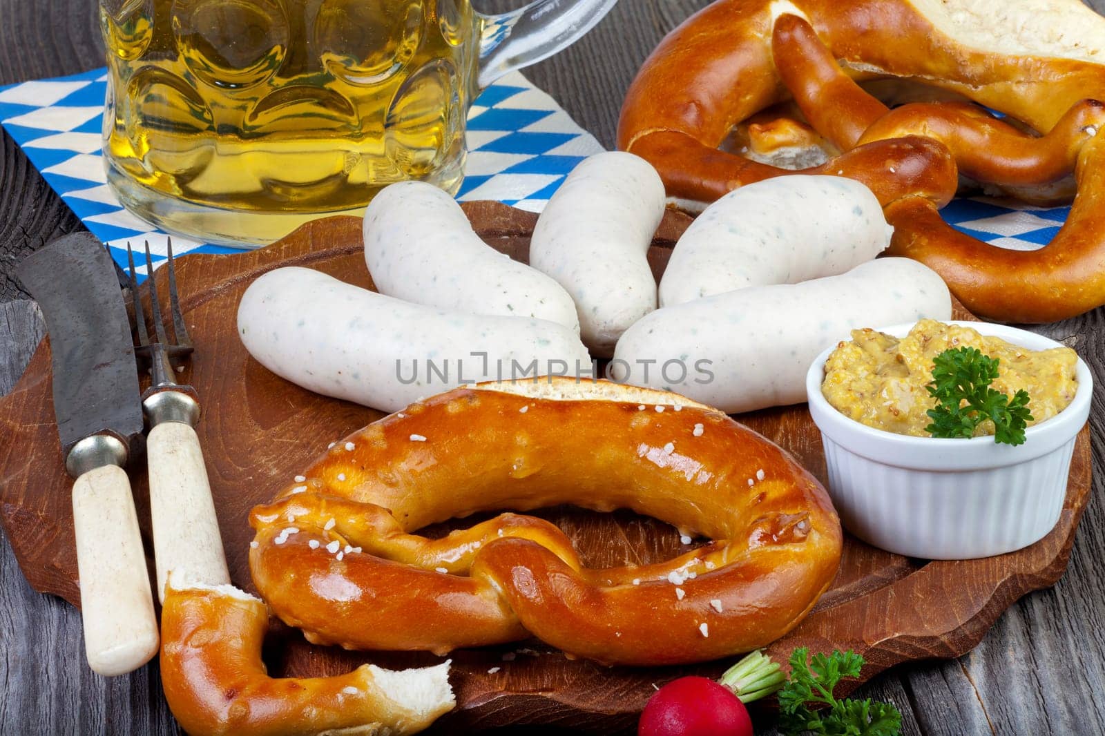 Typical Bavarian Oktoberfest meal with veal sausage,mustard,pretzels and a cold beer on a rustic Holzti