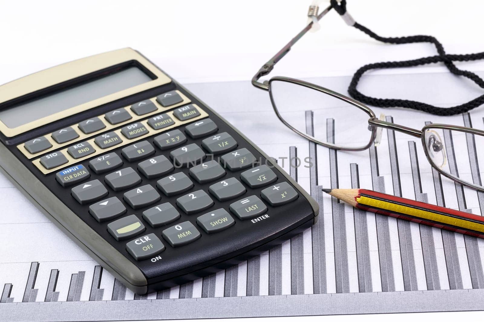 Pen, glasses and calculator on paper table with finance diagram