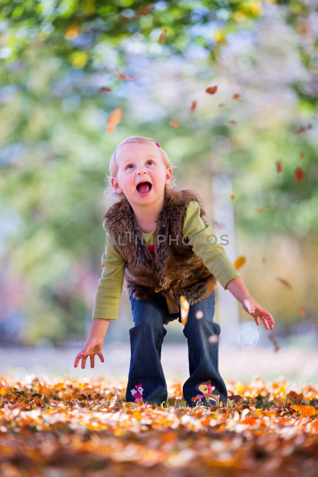 cute little girl throwing autumn leaves