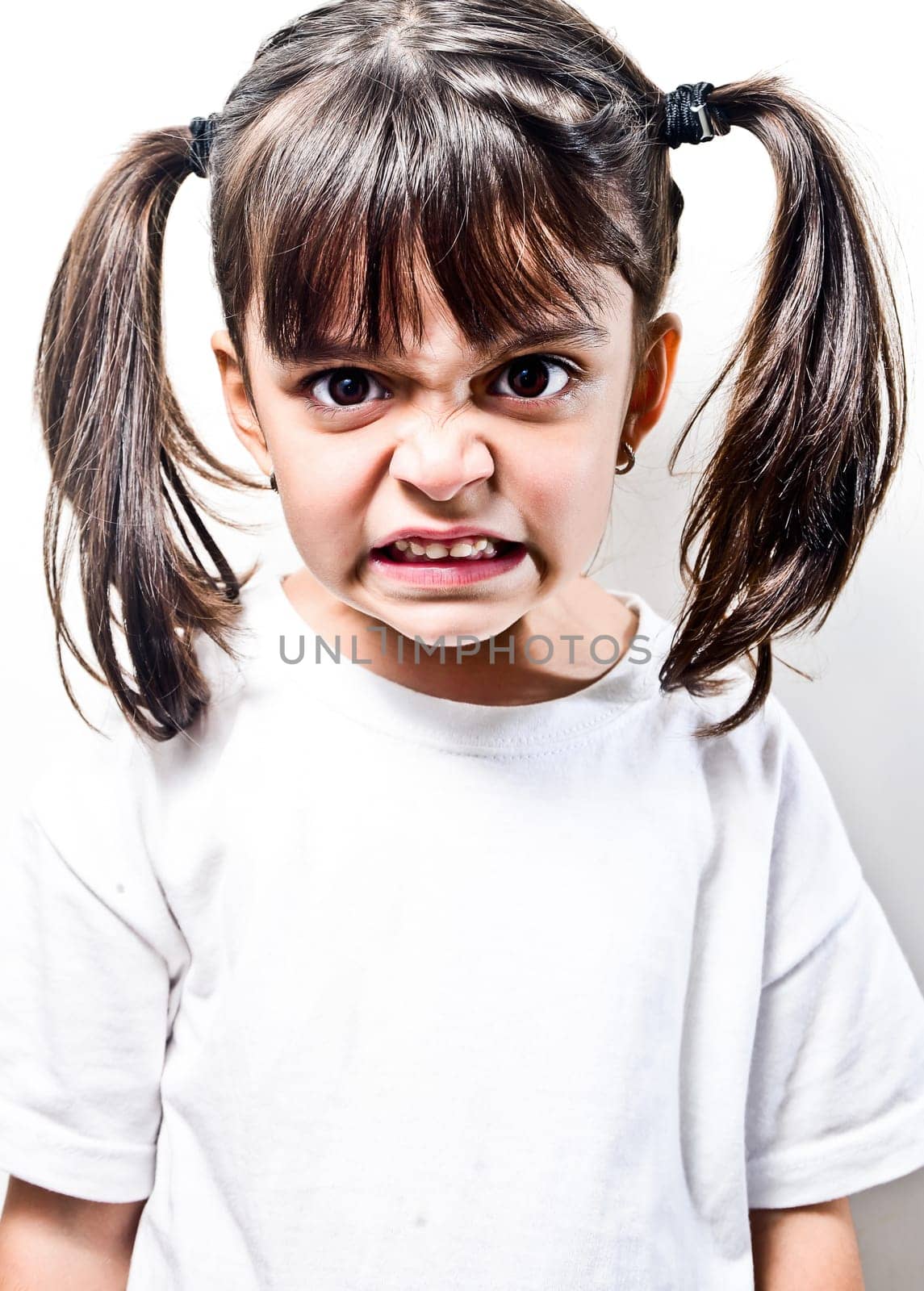 little girl with pigtails very angry on a white background