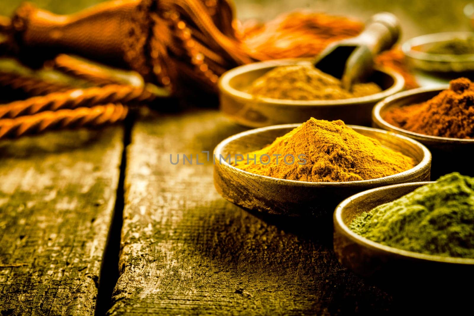 Asian cuisine with a low angle view of bowls of colourful spices with focus to a bowl of turmeric based curry powder