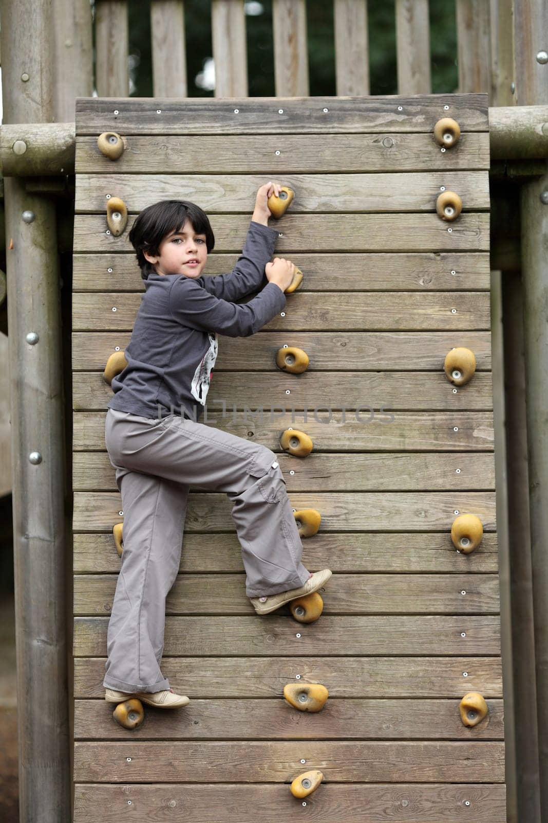Details of an outdoors climbing girl on a climbing wall for kid.