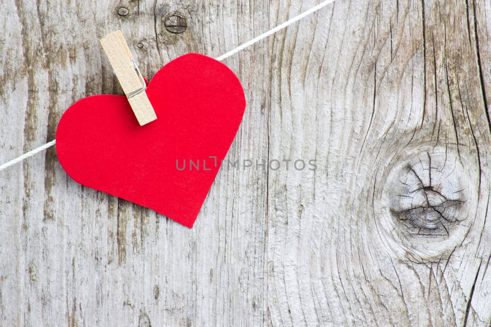 red heart hanging on line against old wood-grain wall