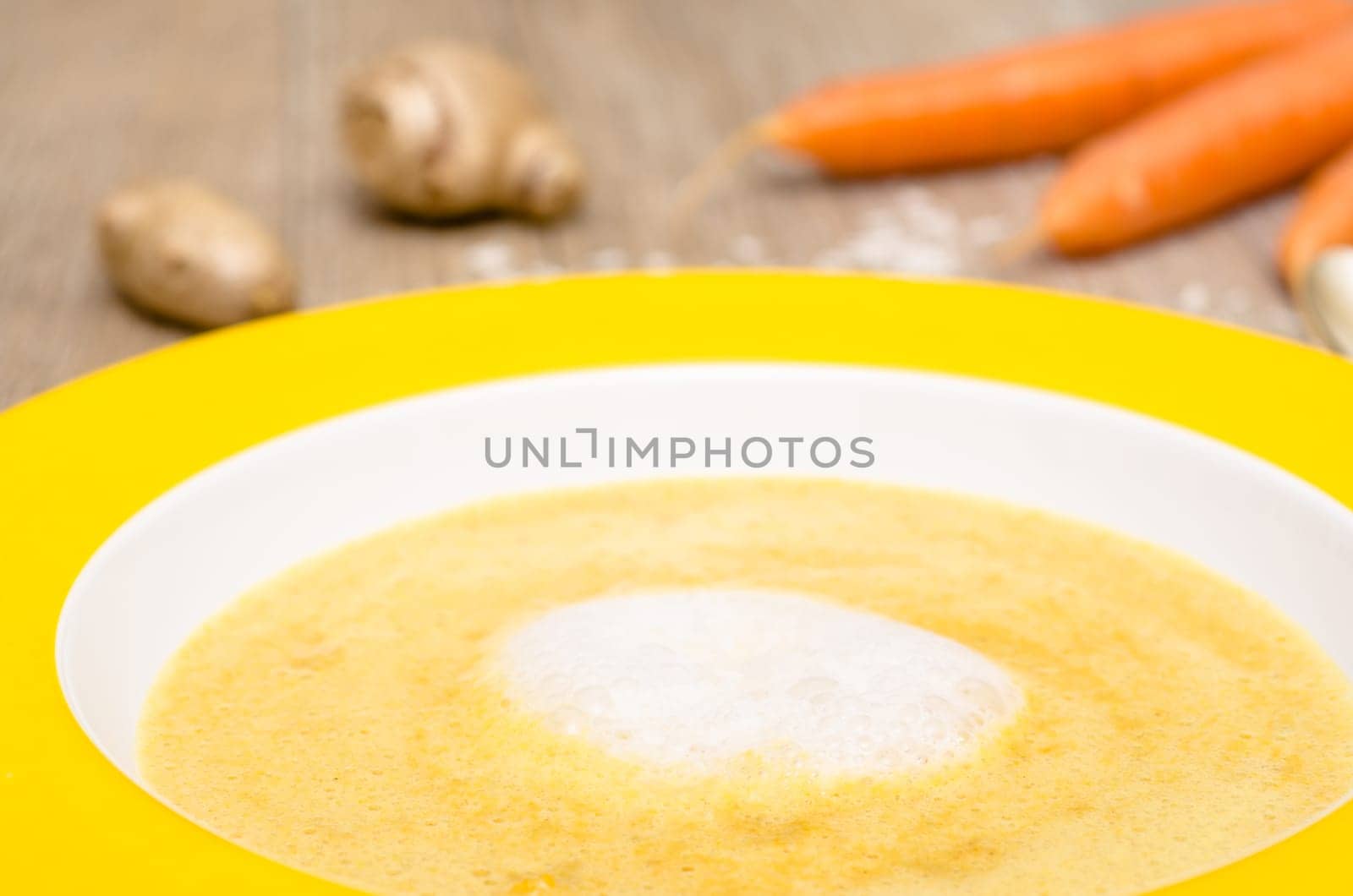 Foam of coconut milk on soup with carrots in a plate