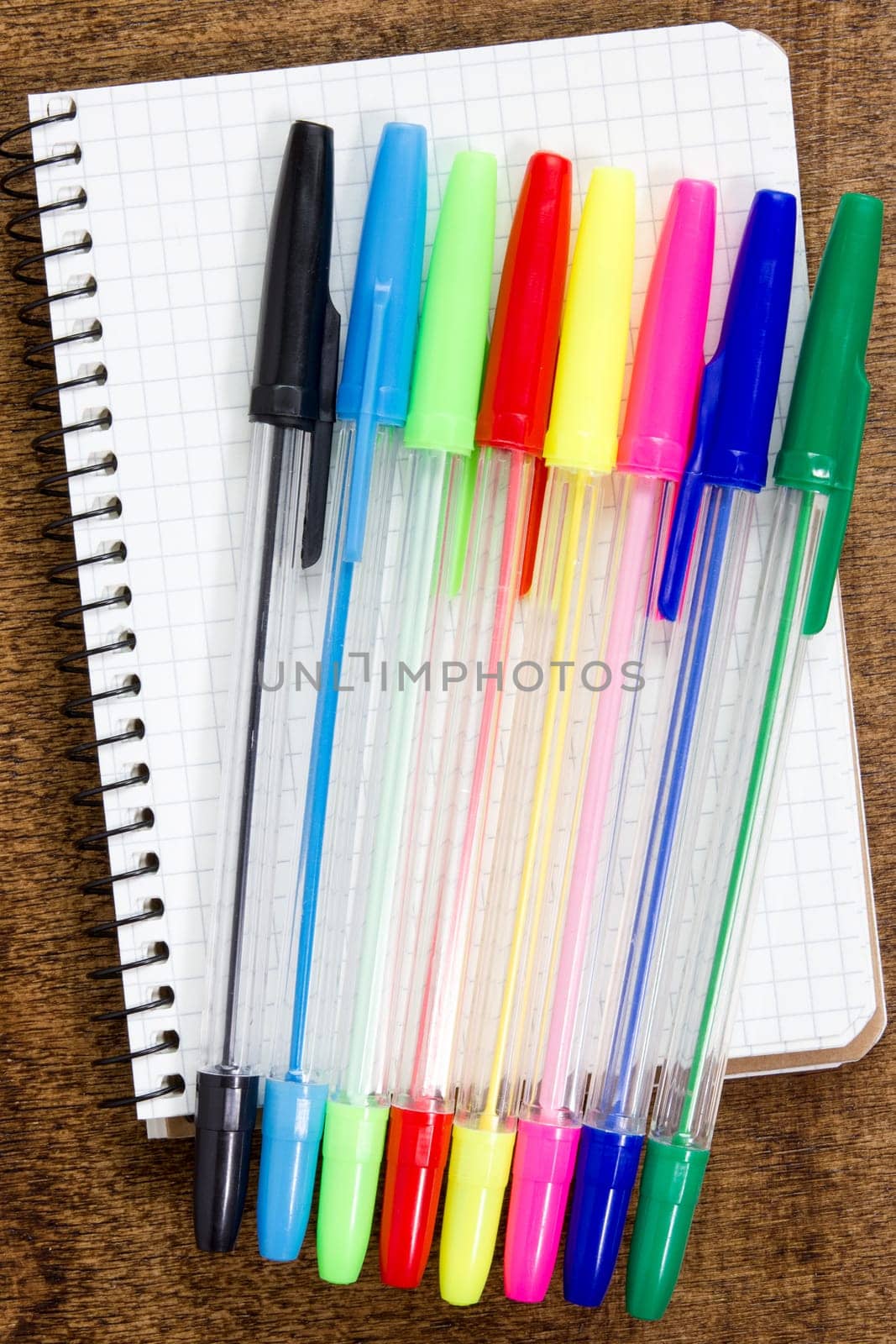 Colorful pens and spiral notebook on the wooden desk