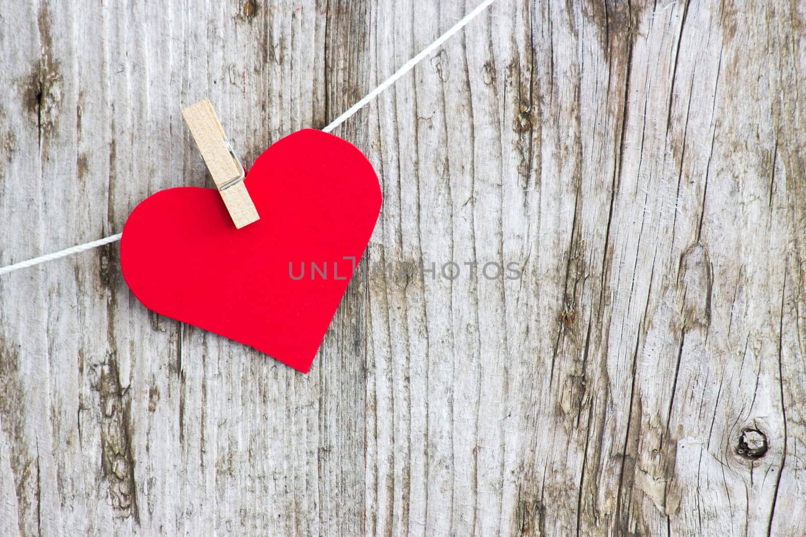 red heart hanging on line against old wood-grain wall
