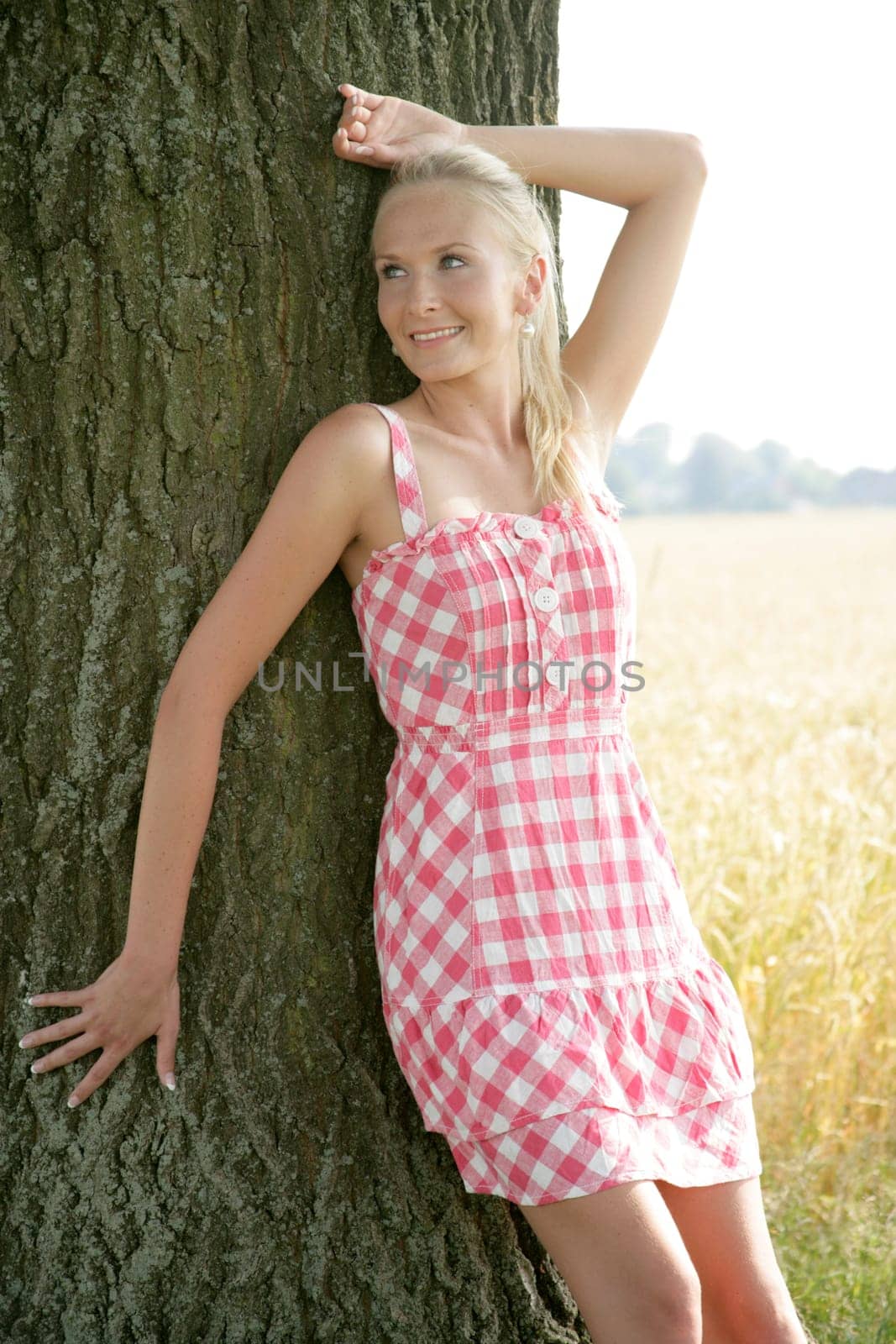 Young woman leaning against a tree