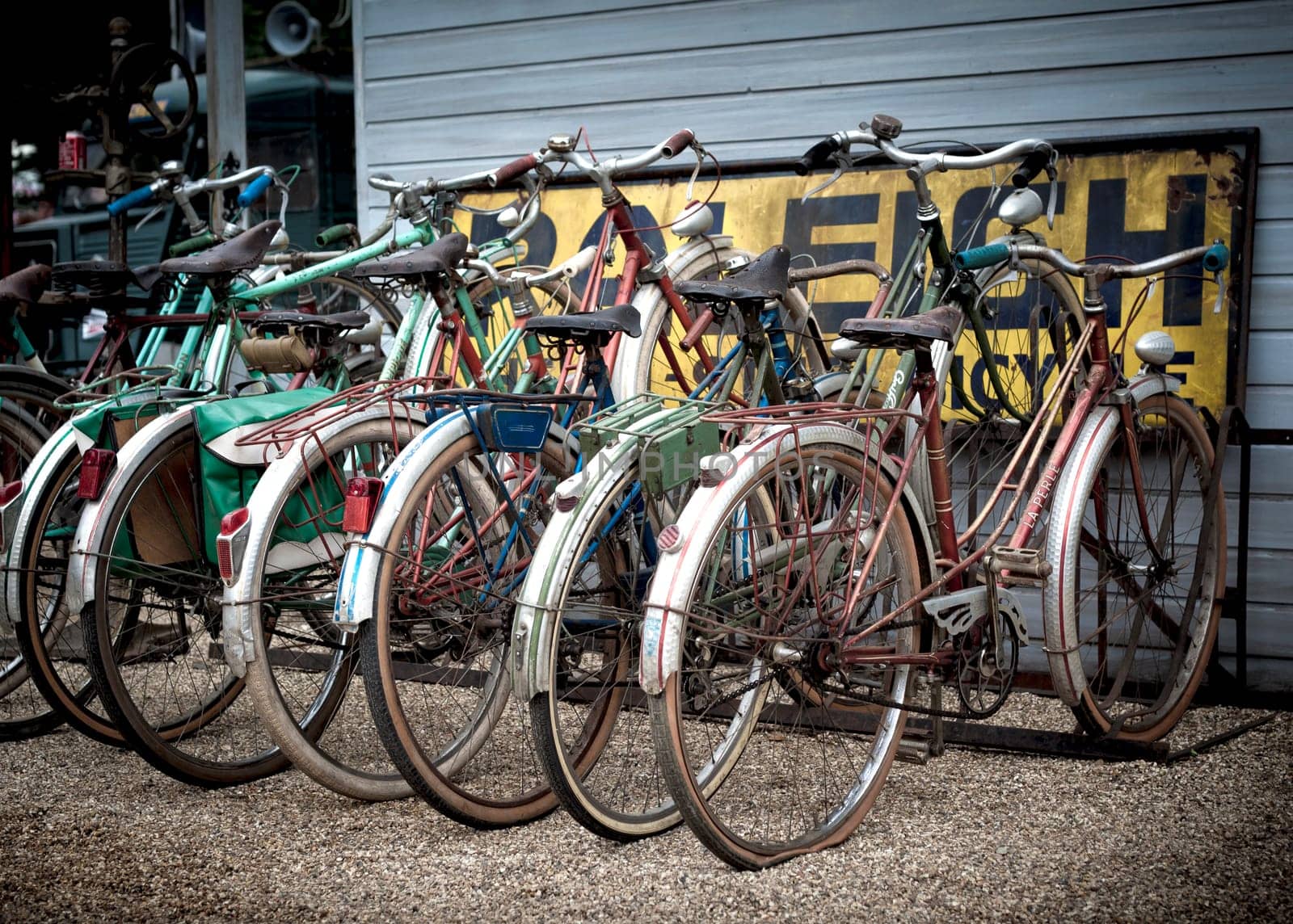 A group of old rusty retro pushbikes parked in a row.