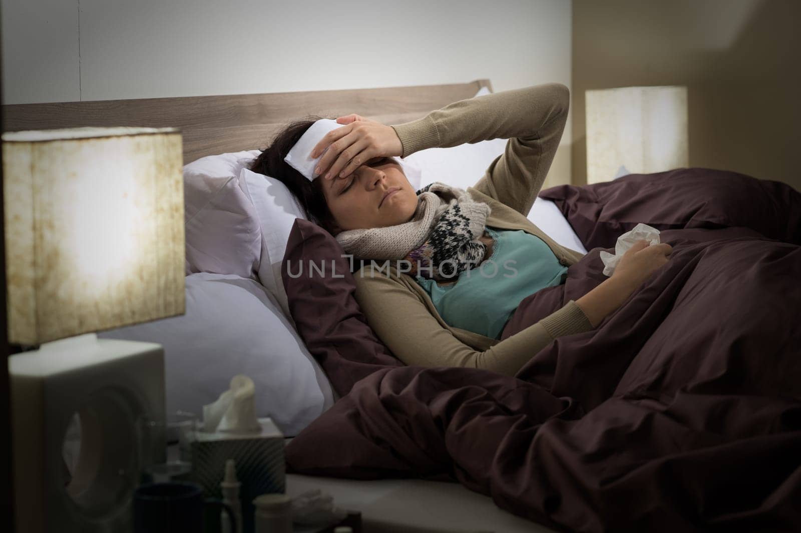 Young Caucasian woman lying sick in bed suffering from cold
