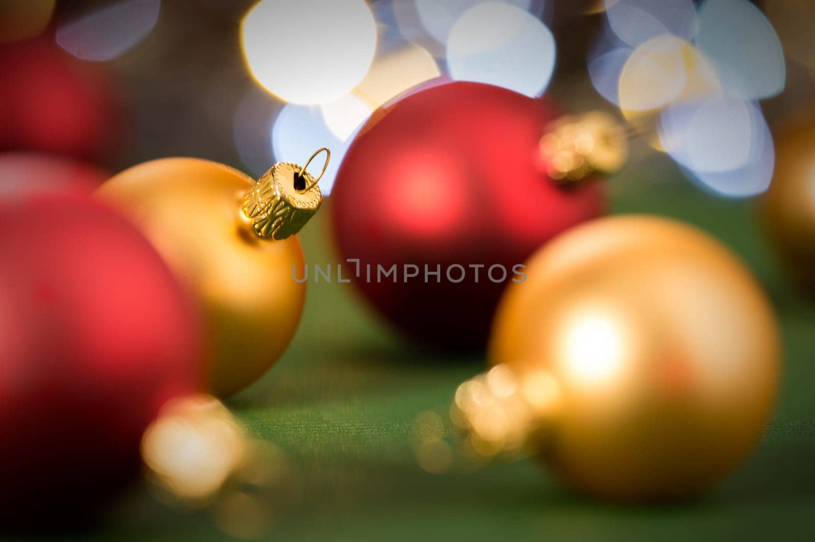 Gold and red christmas baubles on green lights background