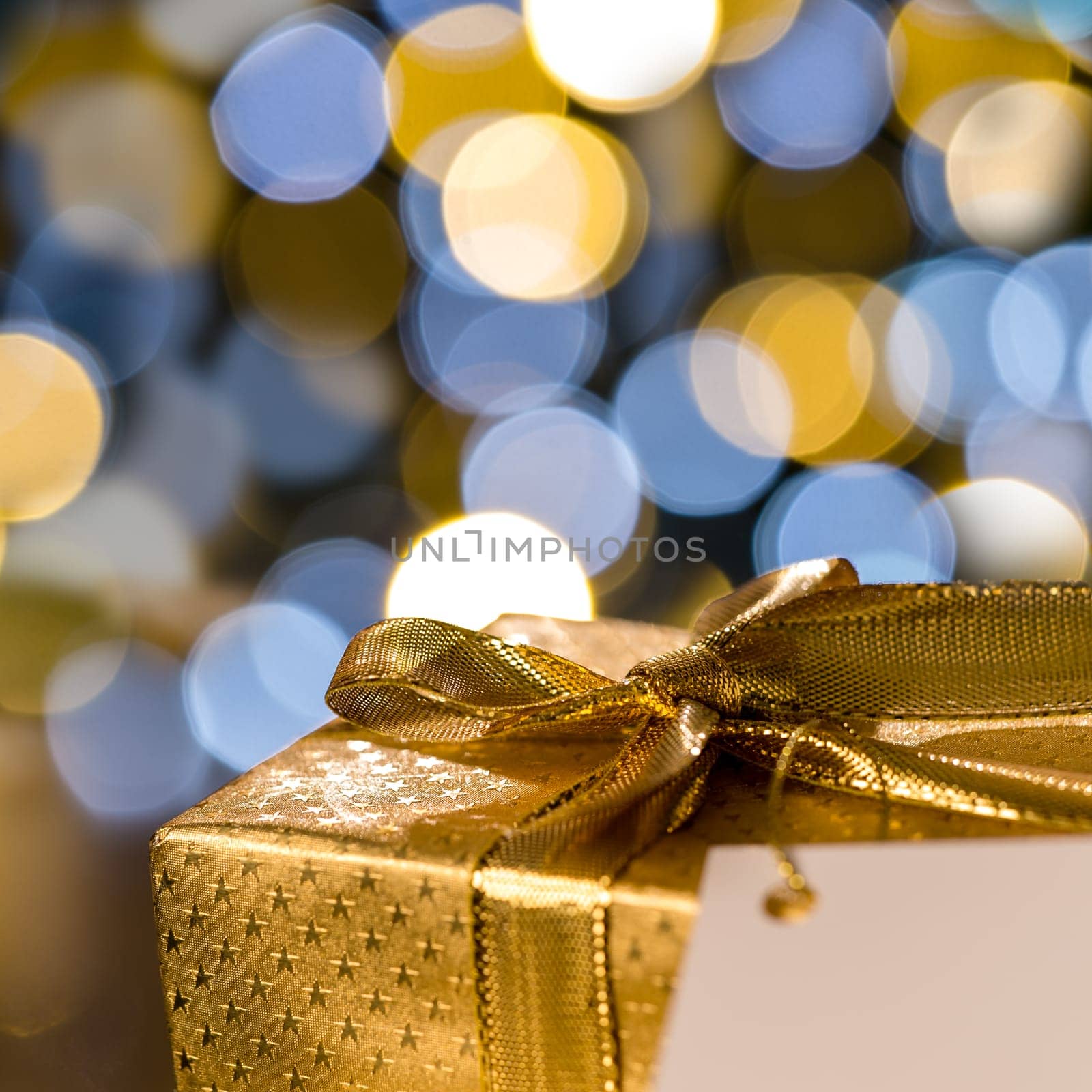Golden Christmas gift with label sparkling lights on background