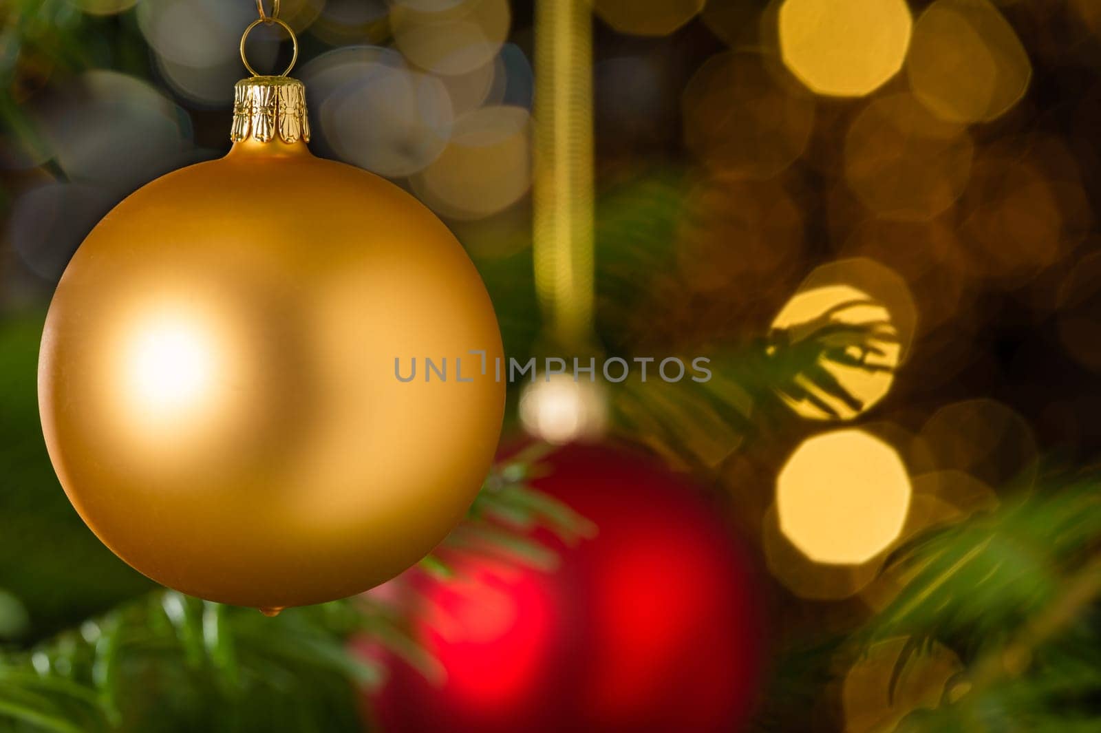 Gold christmas bauble hanging on Xmas tree sparkling lights background